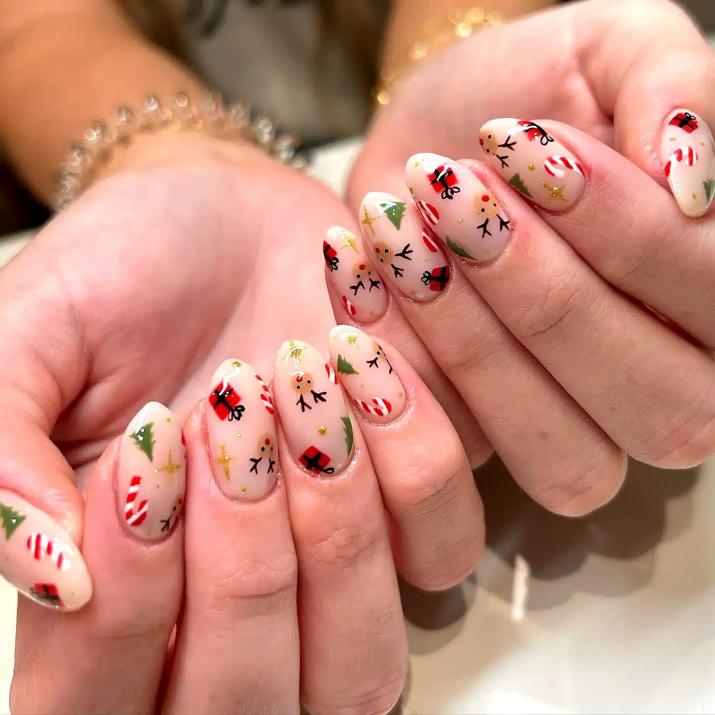 Adorable almond-shaped reindeer nail designs in festive nude with candy canes Christmas trees and Santa motifs