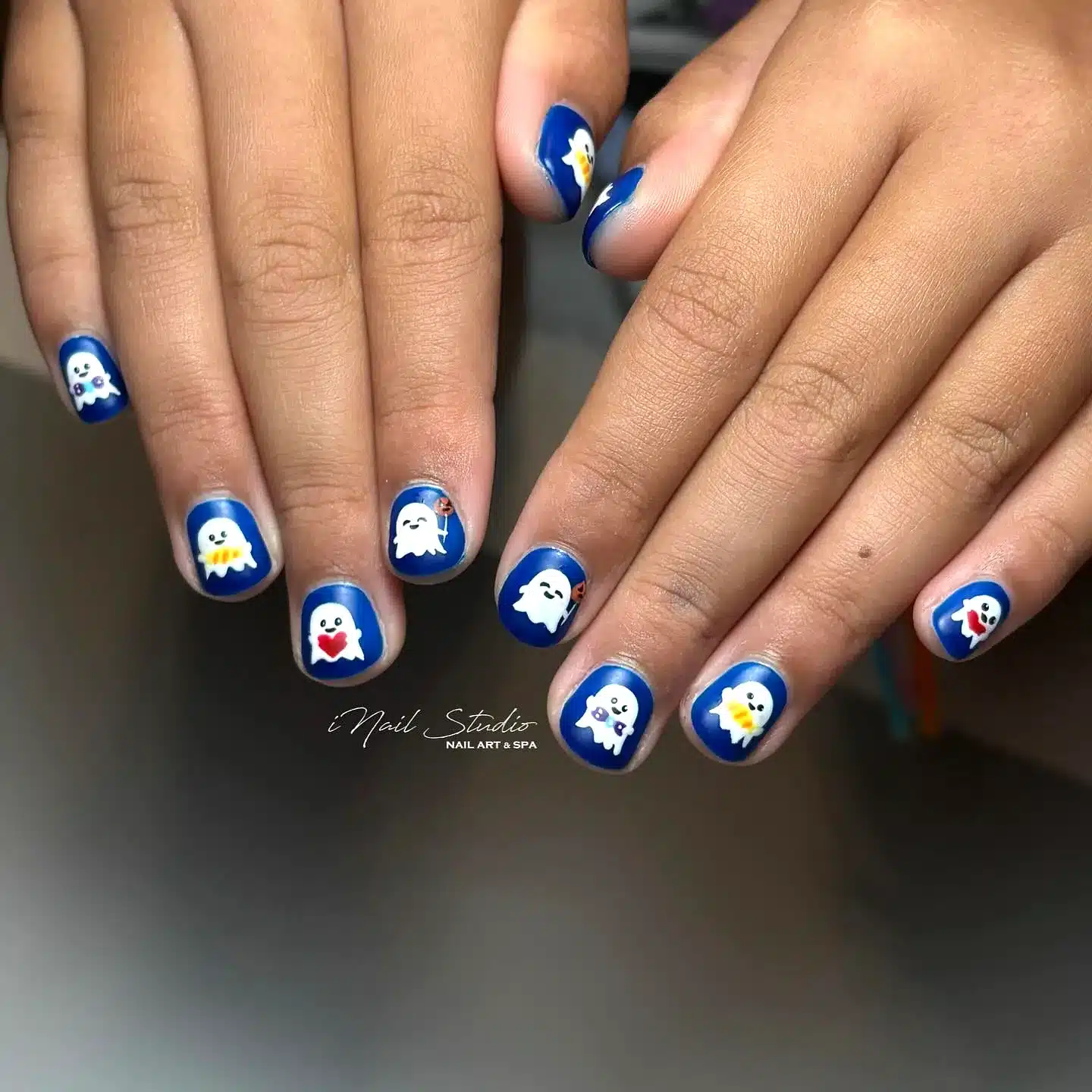 Adorable Rounded Halloween Nails for Kids with Vibrant Blue Background and Playful Ghost Designs