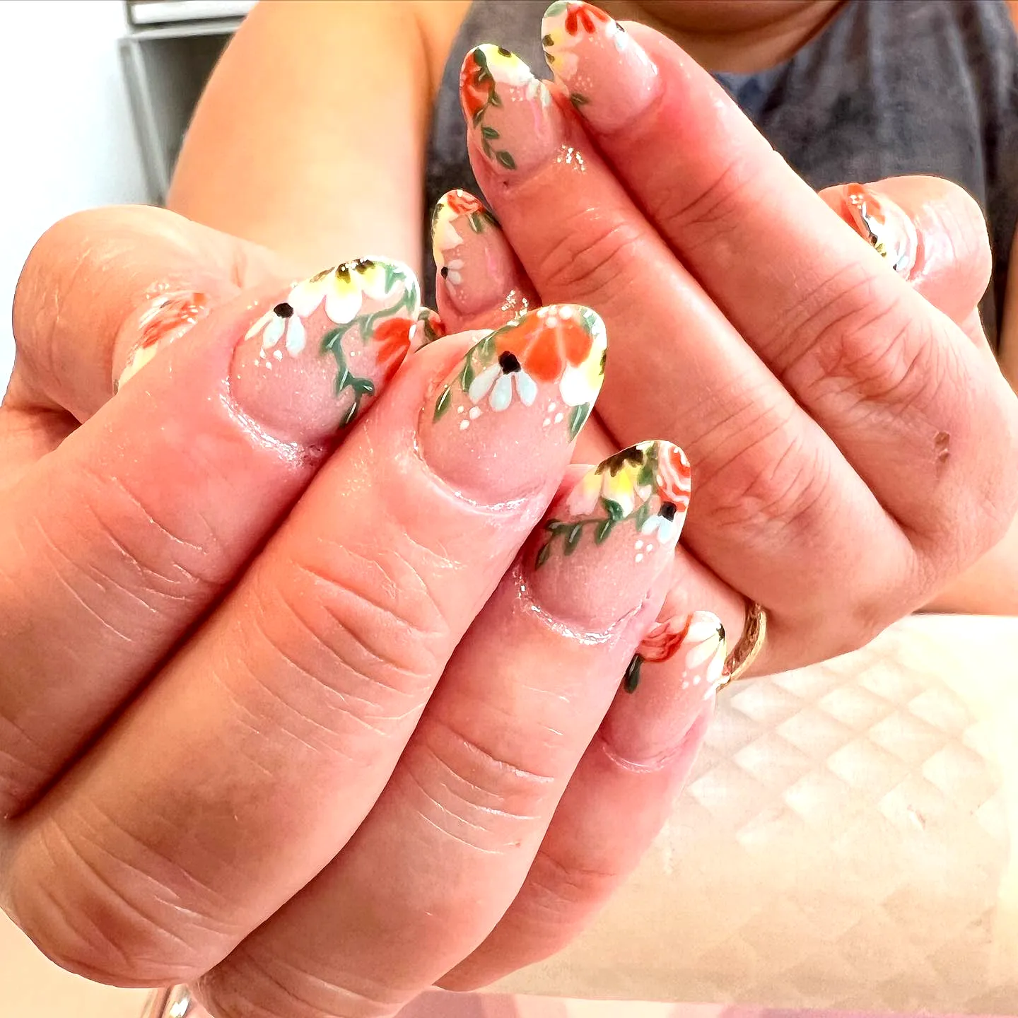 Charming almond-shaped gothic easter nails with floral designs in nude and vibrant orange hues