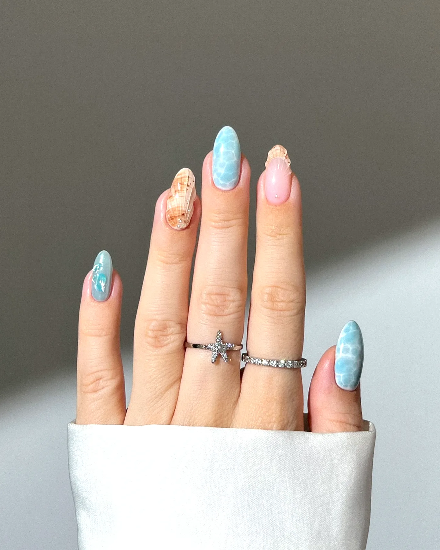 Charming almond-shaped summer nail designs with glossy blue patterns and playful pink accents