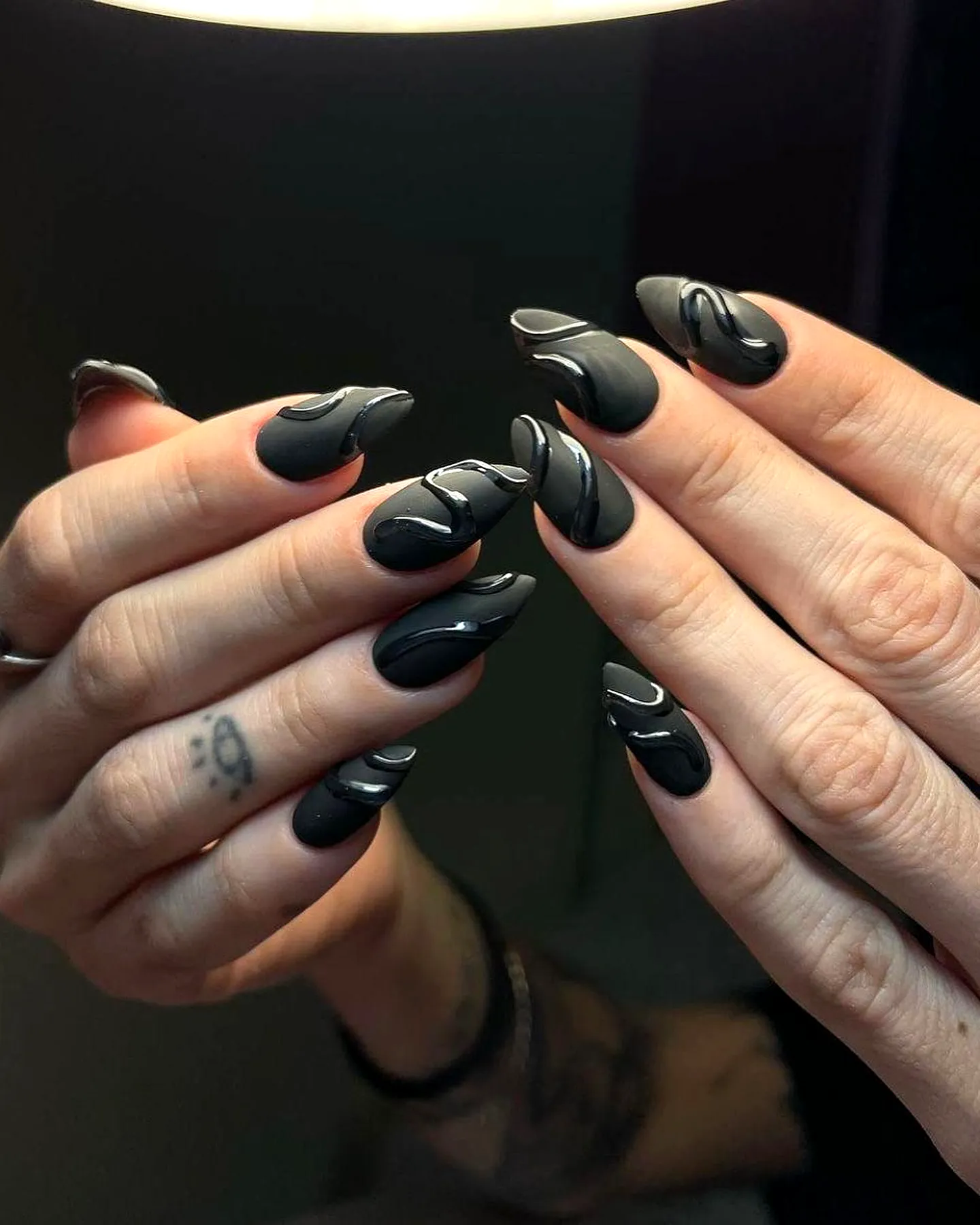 Chic Almond-Shaped Black Nails with Elegant White Swirls for Modern Nail Art