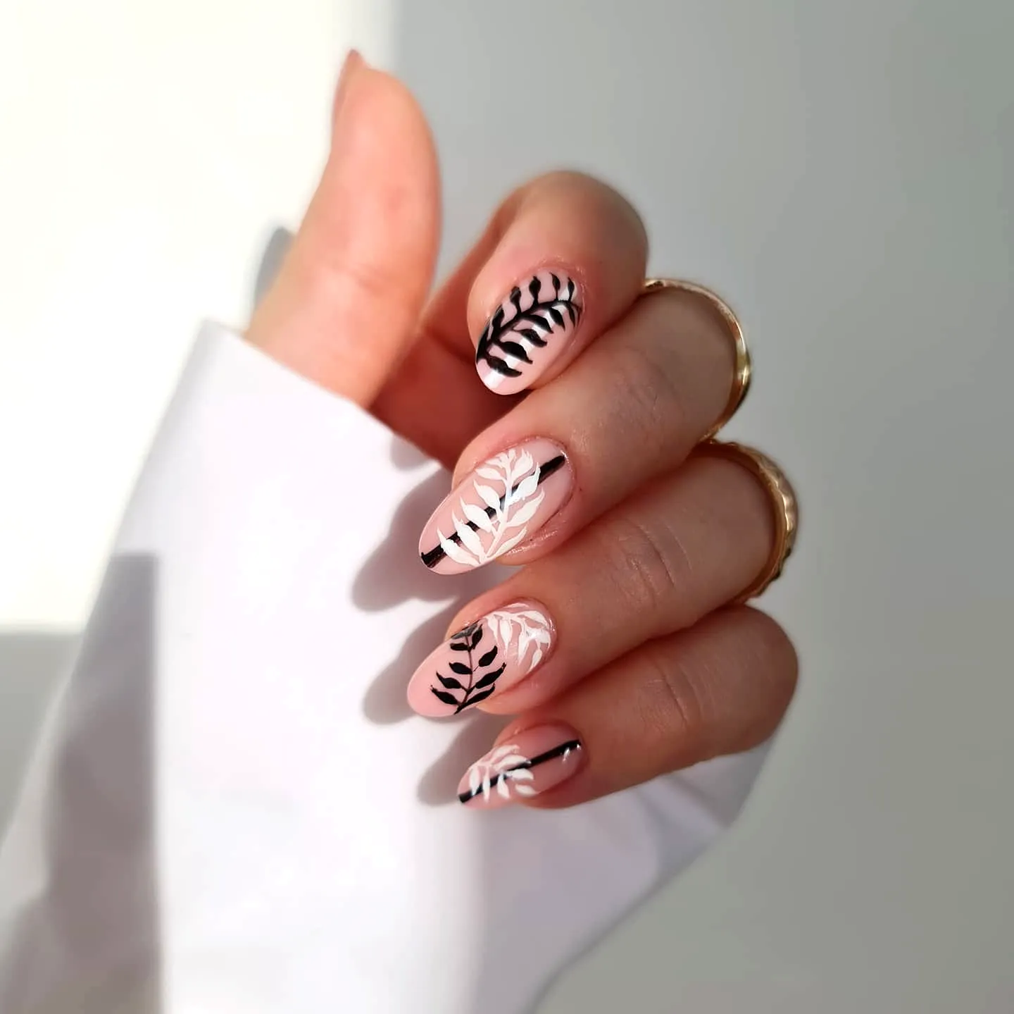 Chic Almond-Shaped Leaf Nail Designs with Soft Pink Base and Elegant Black and White Patterns