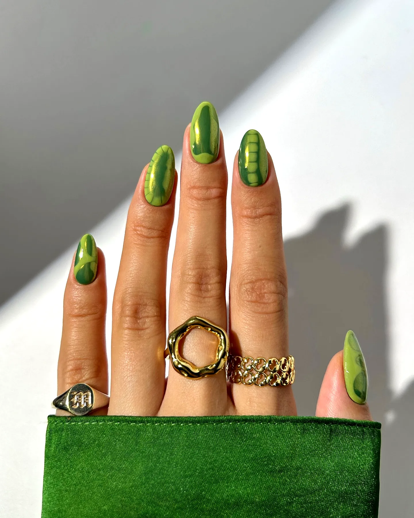 Chic Almond Shaped Olive Green Nails with Abstract Patterns and Metallic Accents