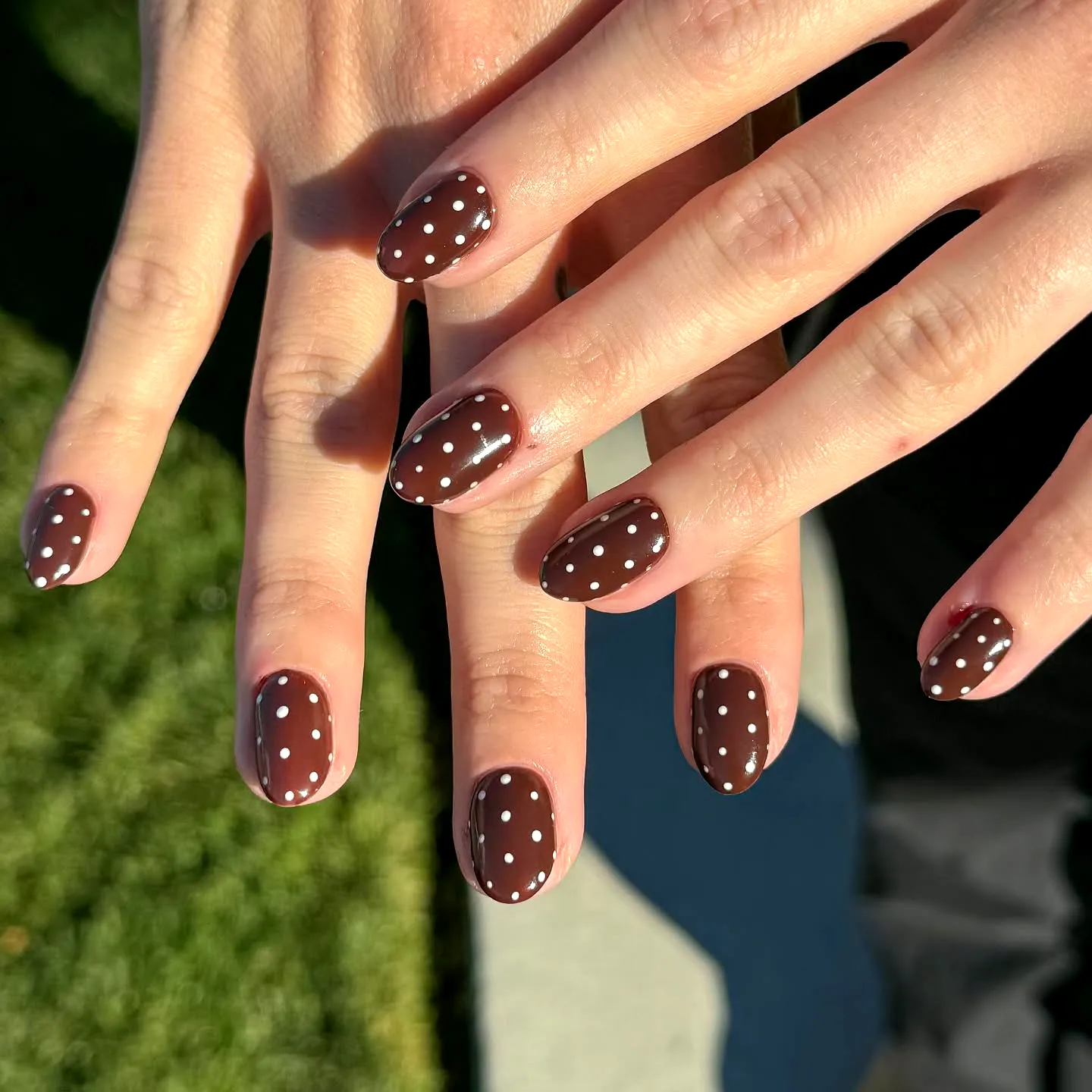 Chic Oval Brown Nails with Playful White Polka Dots for a Modern Look
