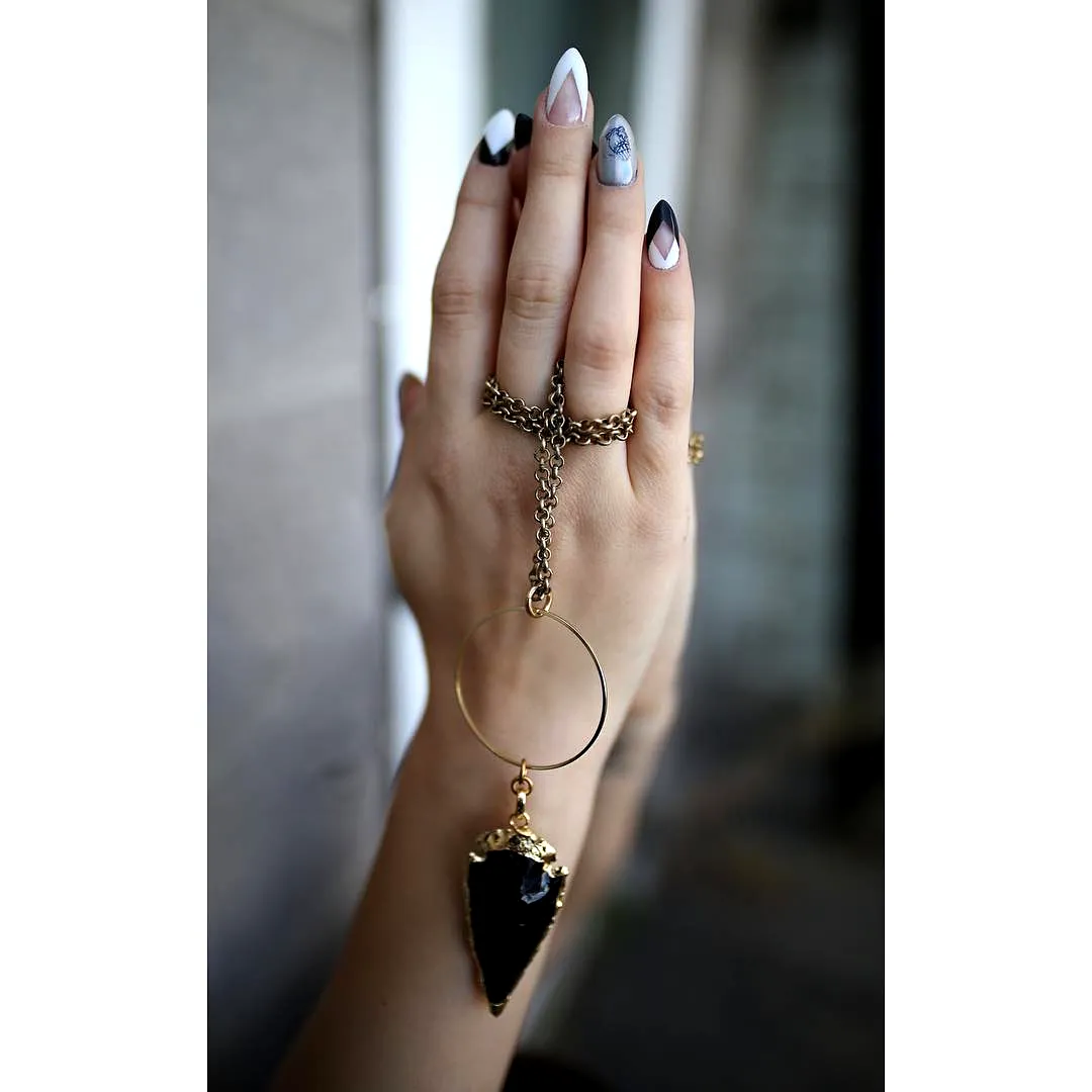 Chic Stiletto Arrowhead Nails with Black and White Geometric Patterns and Metallic Accents