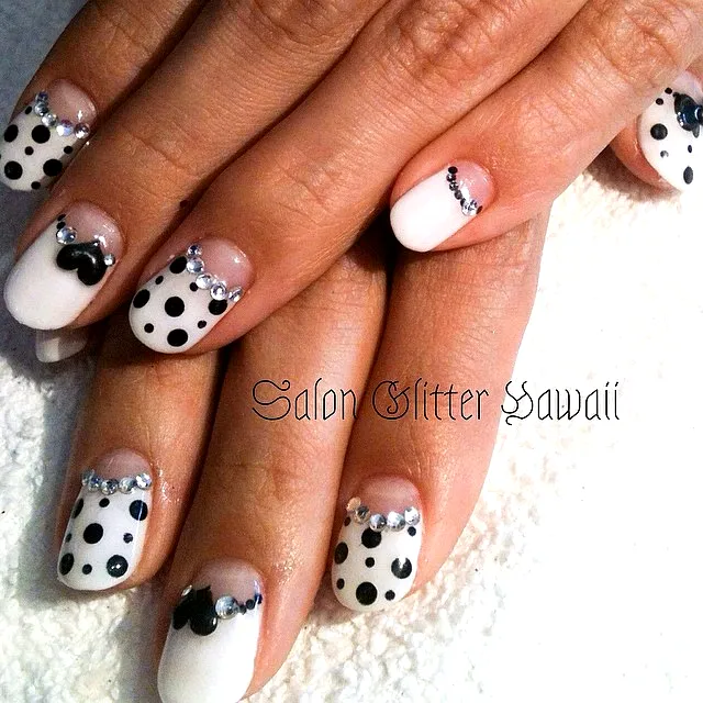 Cute almond shaped black and white polka dot nails with rhinestones and heart accents