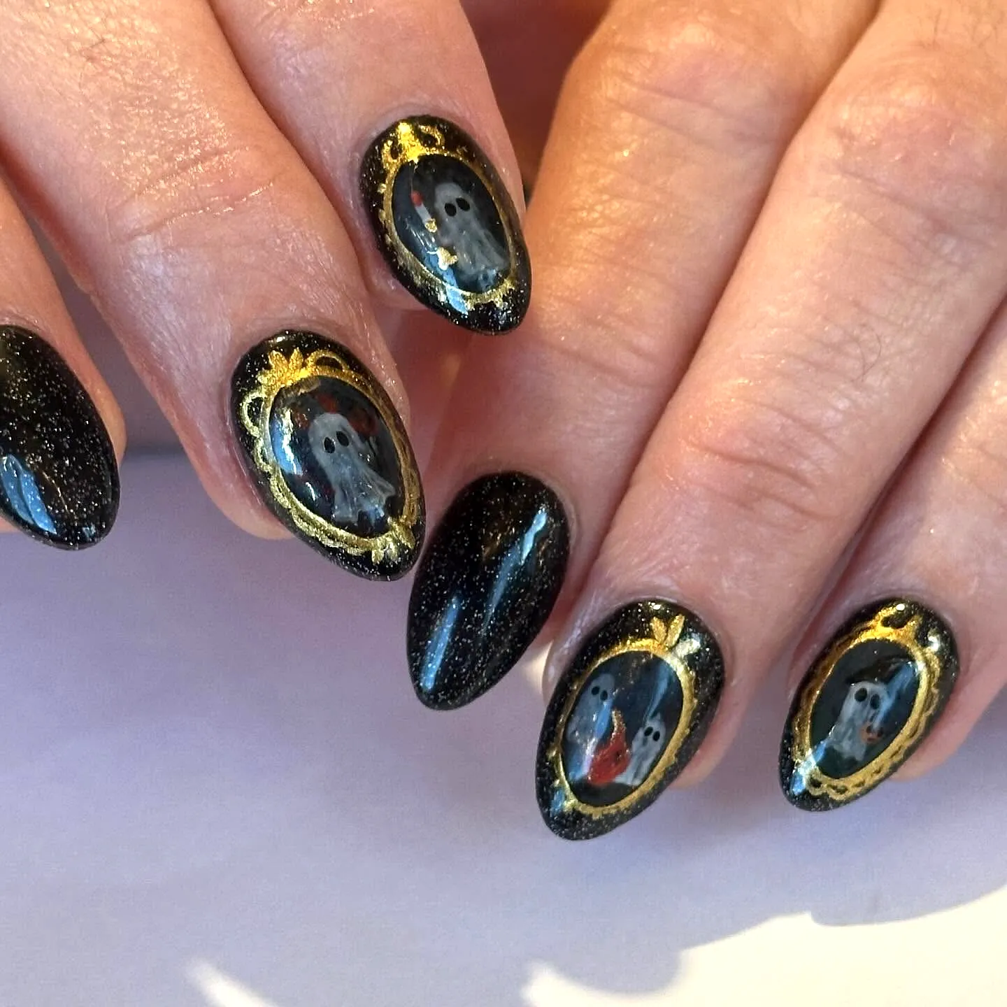 Cute almond-shaped black Halloween nails for kids featuring vintage ghost portraits and shimmering finishes