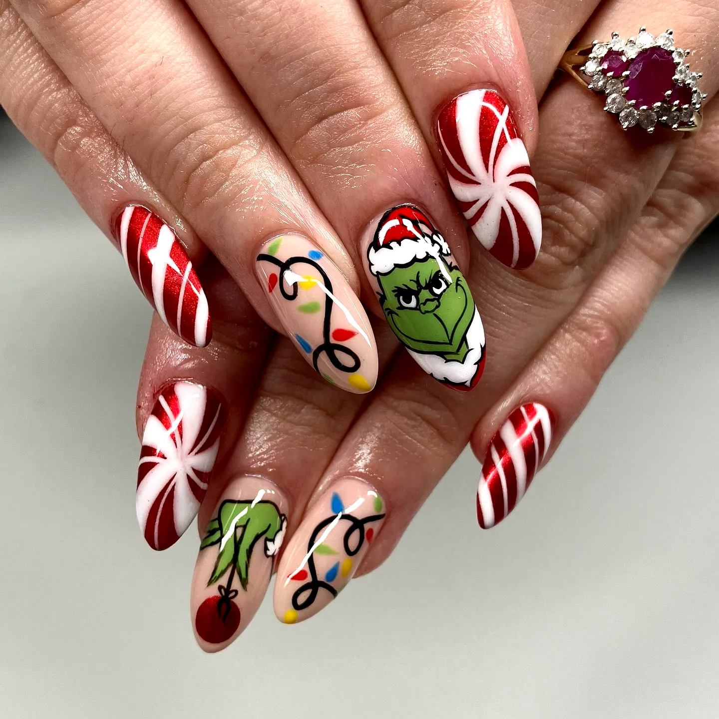 Cute Almond Shaped Grinch Nails Featuring Colorful Christmas Lights and Candy Cane Patterns in Festive Red White and Green Styles