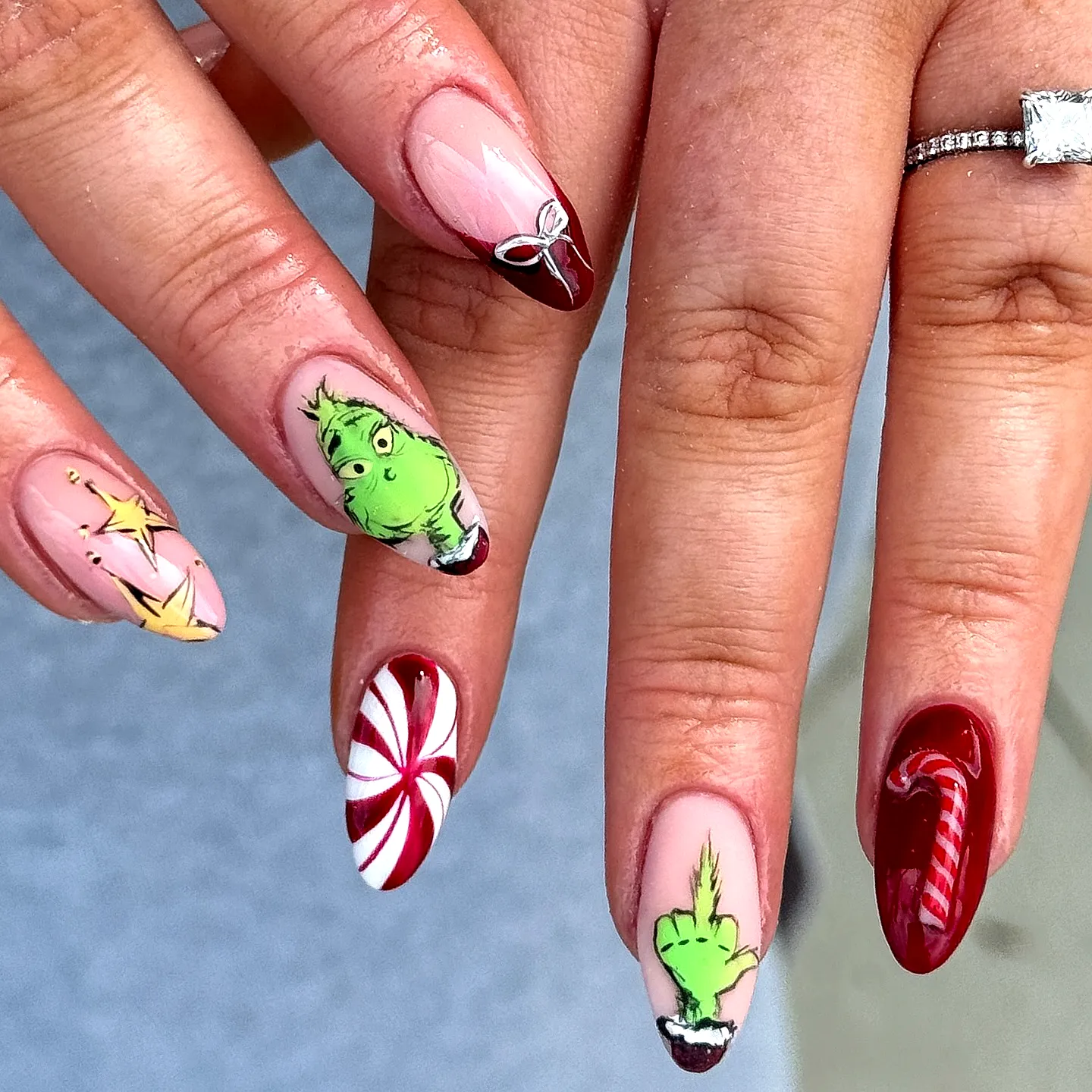 Cute Almond-Shaped Grinch Nails with Festive Candy Canes and Gold Stars in Red White and Green