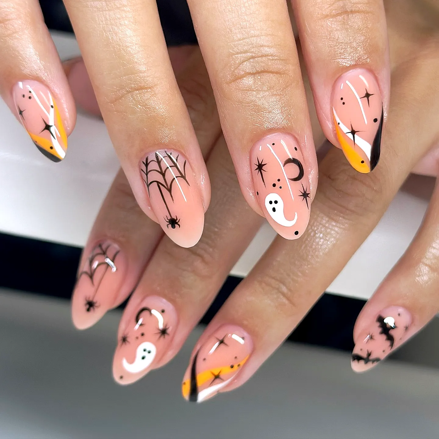 Cute Almond Shaped Nude Halloween Nails with Whimsical Ghosts Spiders and Moons
