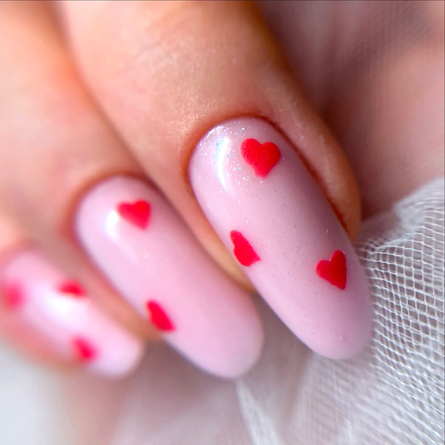 Cute almond shaped red heart nails with a soft pink glossy finish