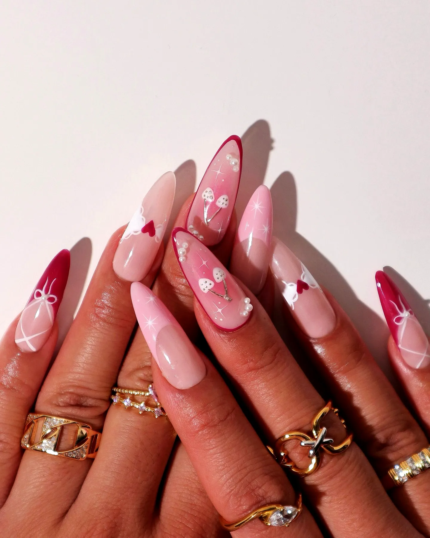 Cute Almond-Shaped Valentines Day Nails with Gradient Pink and Red Colors Featuring Hearts Bows and Pearls