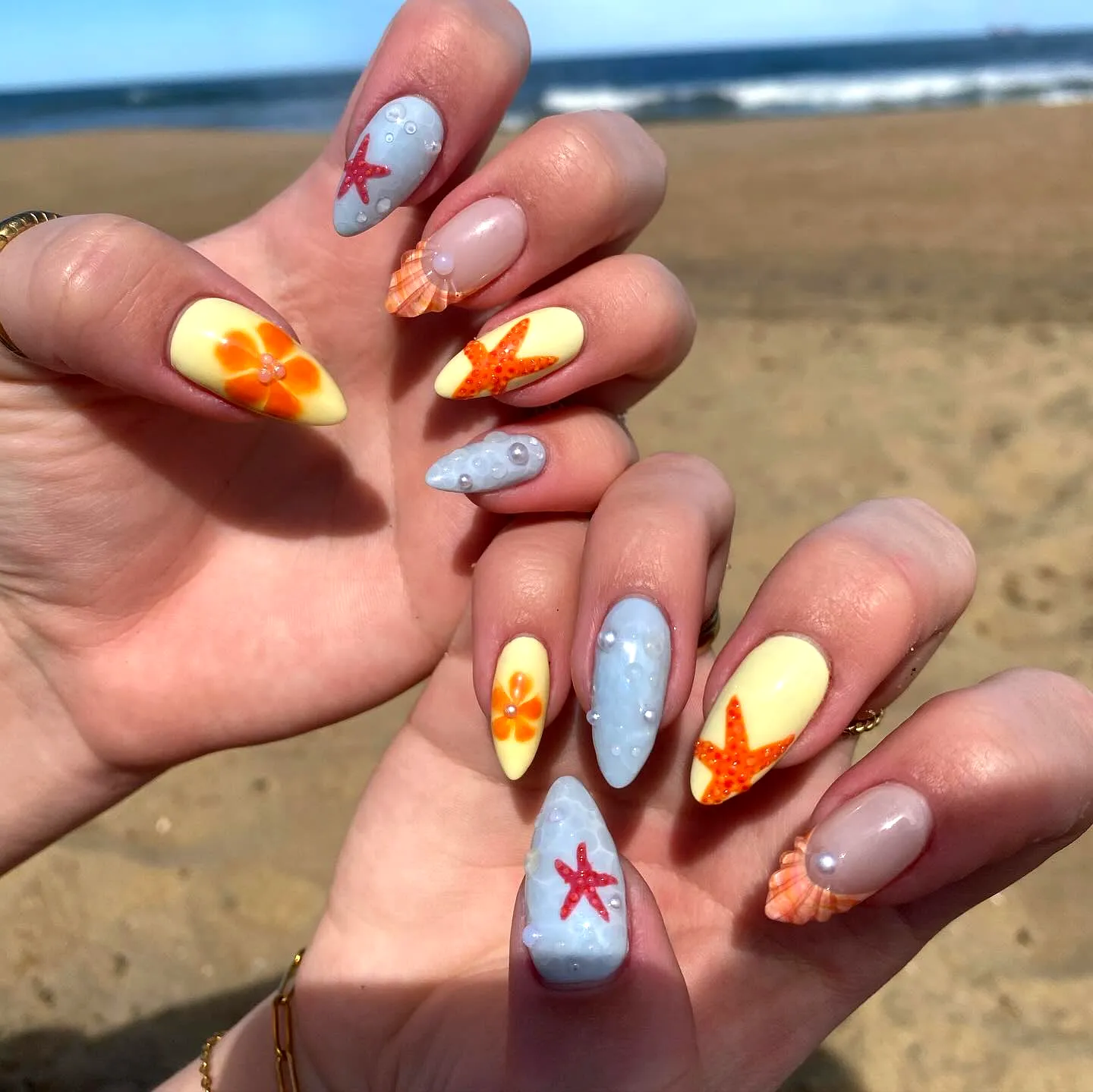 Cute beach nails in stiletto and almond shapes featuring soft pastels starfish and flower embellishments