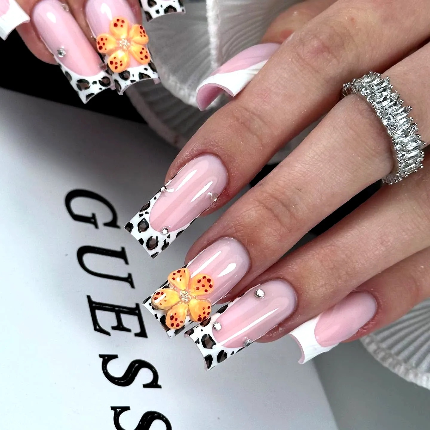Cute coffin ballerina nails with glossy pink base and unique animal print tips featuring orange flower and silver studs