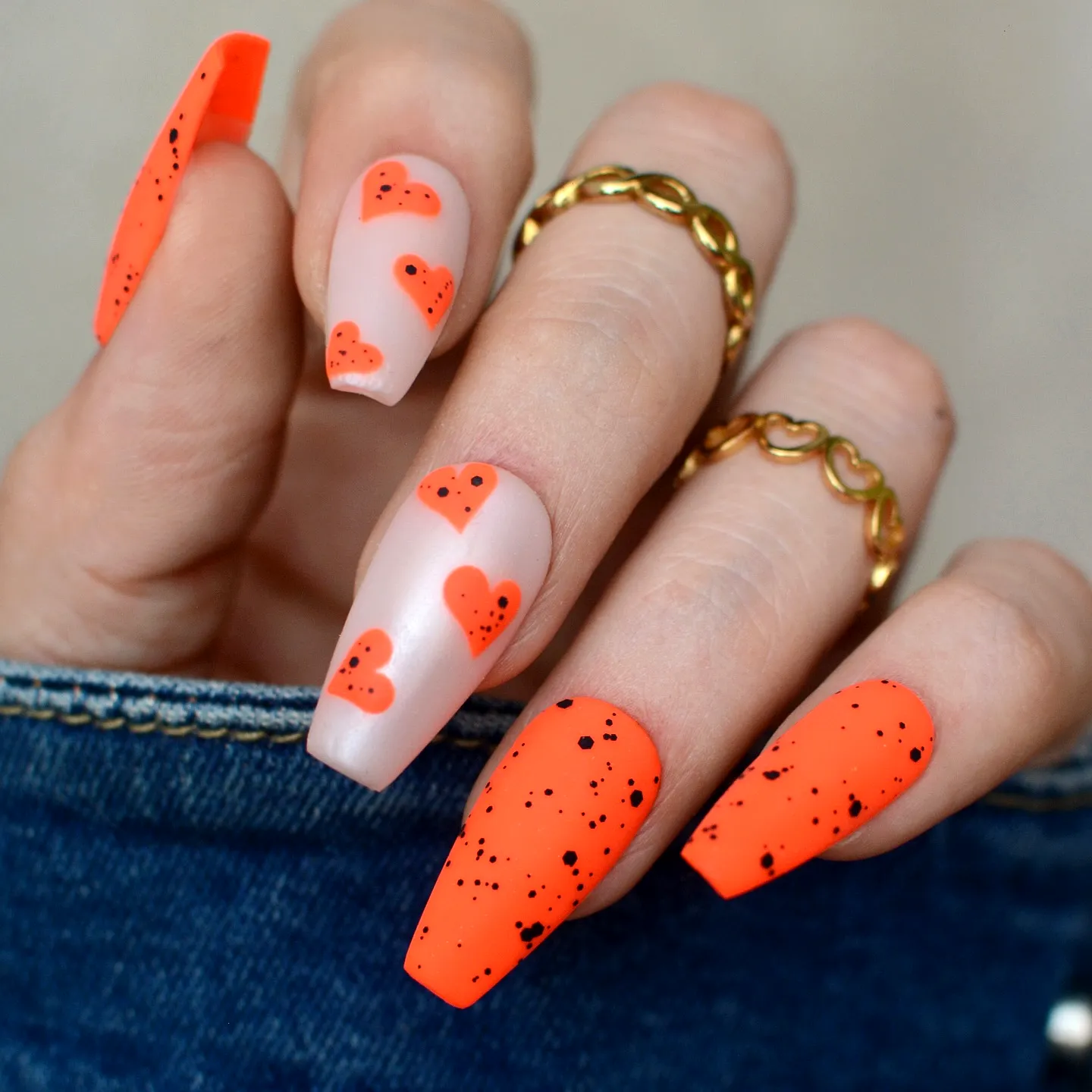 Cute coffin-shaped orange nails with playful heart patterns and glossy accents