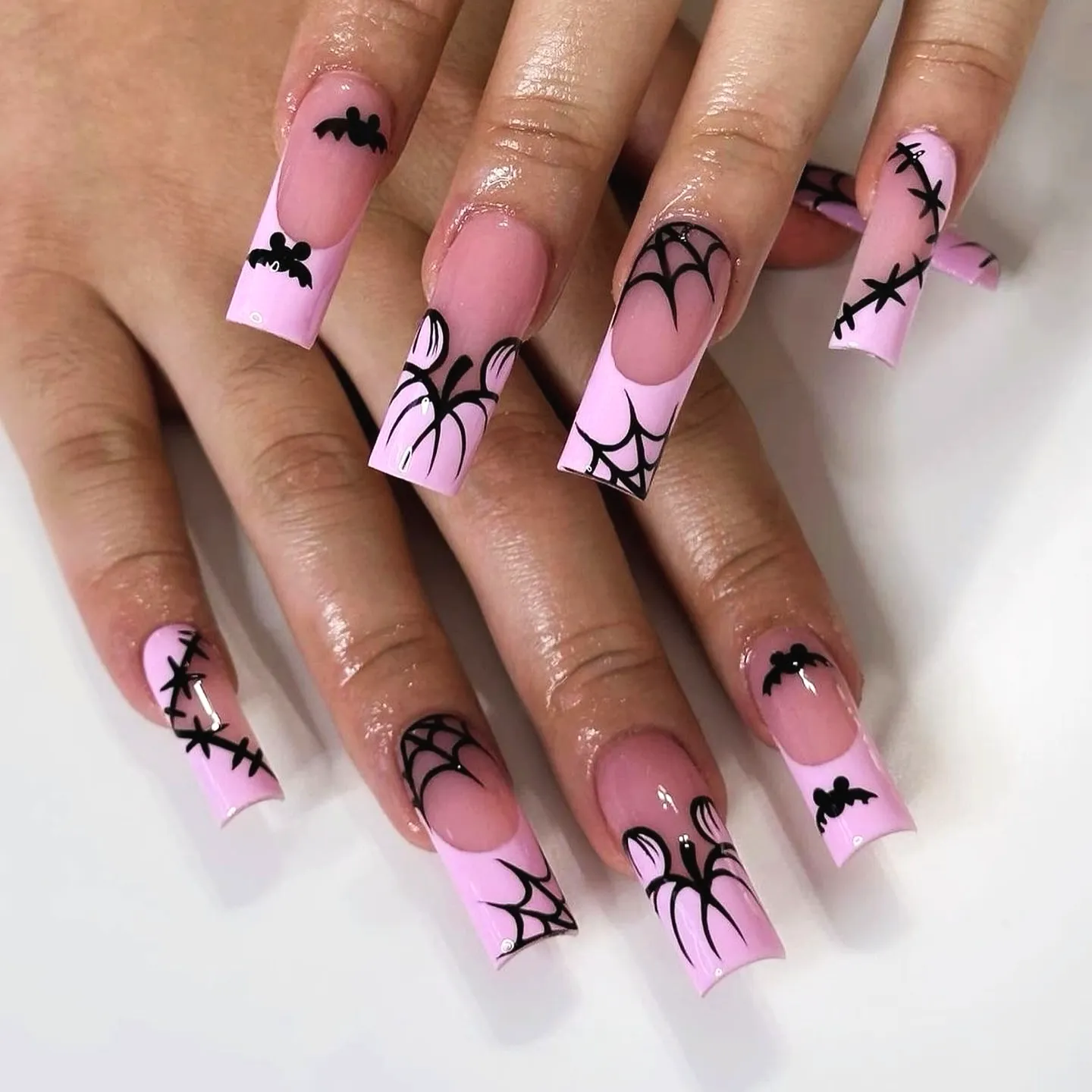 Cute long square Halloween nails with glossy pink base and intricate black spiderweb and bat designs
