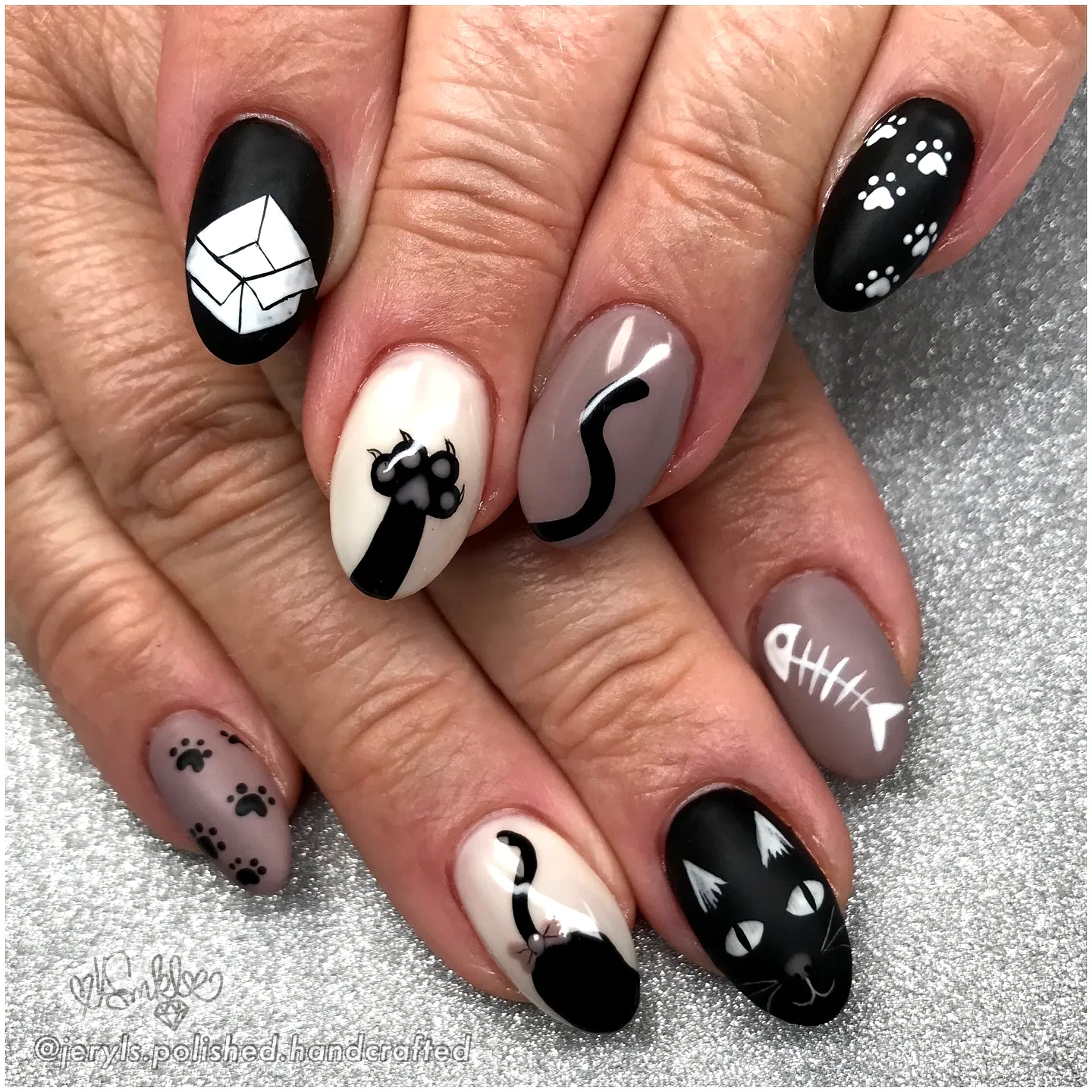 Cute matte black and taupe cat-themed nail art with playful designs in whimsical illustrated style featuring black cat nails