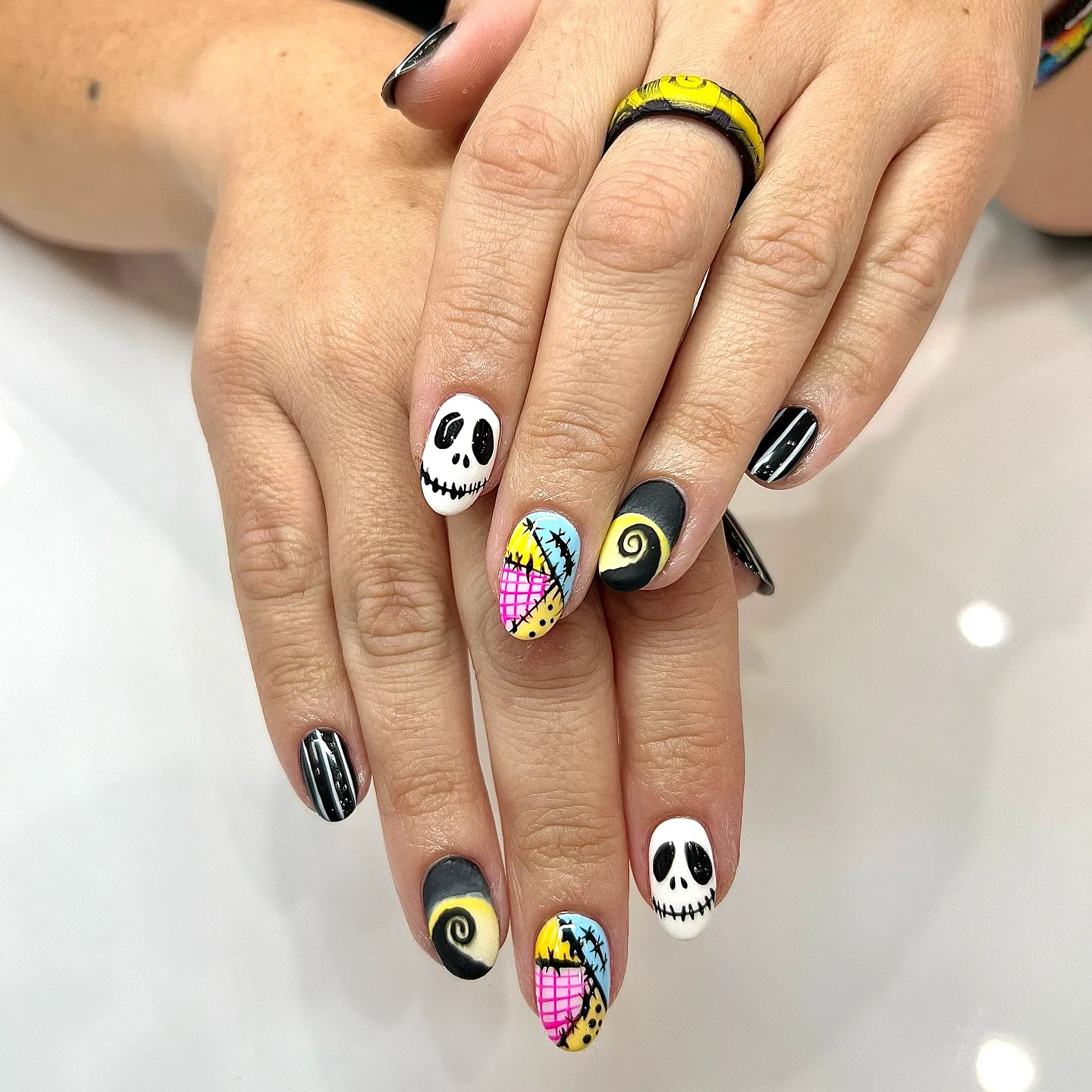 Cute oval Nightmare before Christmas nails with black and white colors playful skulls and pineapple patterns in a cartoonish style