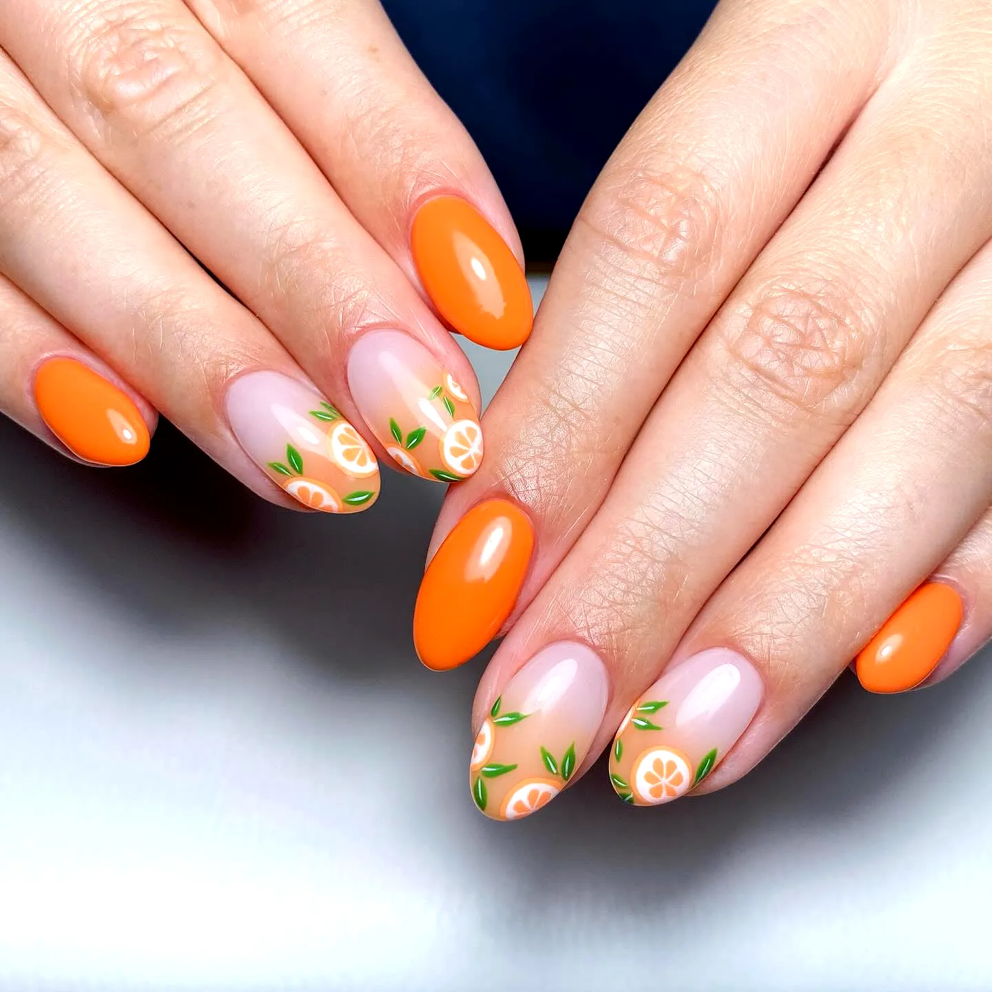 Cute oval orange nails with fruit and floral nail art for a vibrant summer look