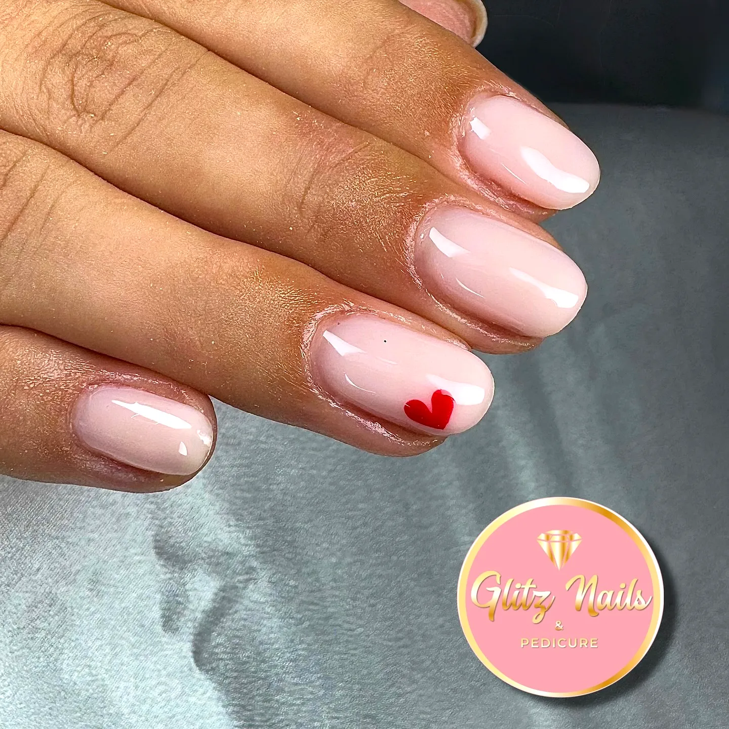 Cute oval soft pink ring finger heart nails with a playful red accent