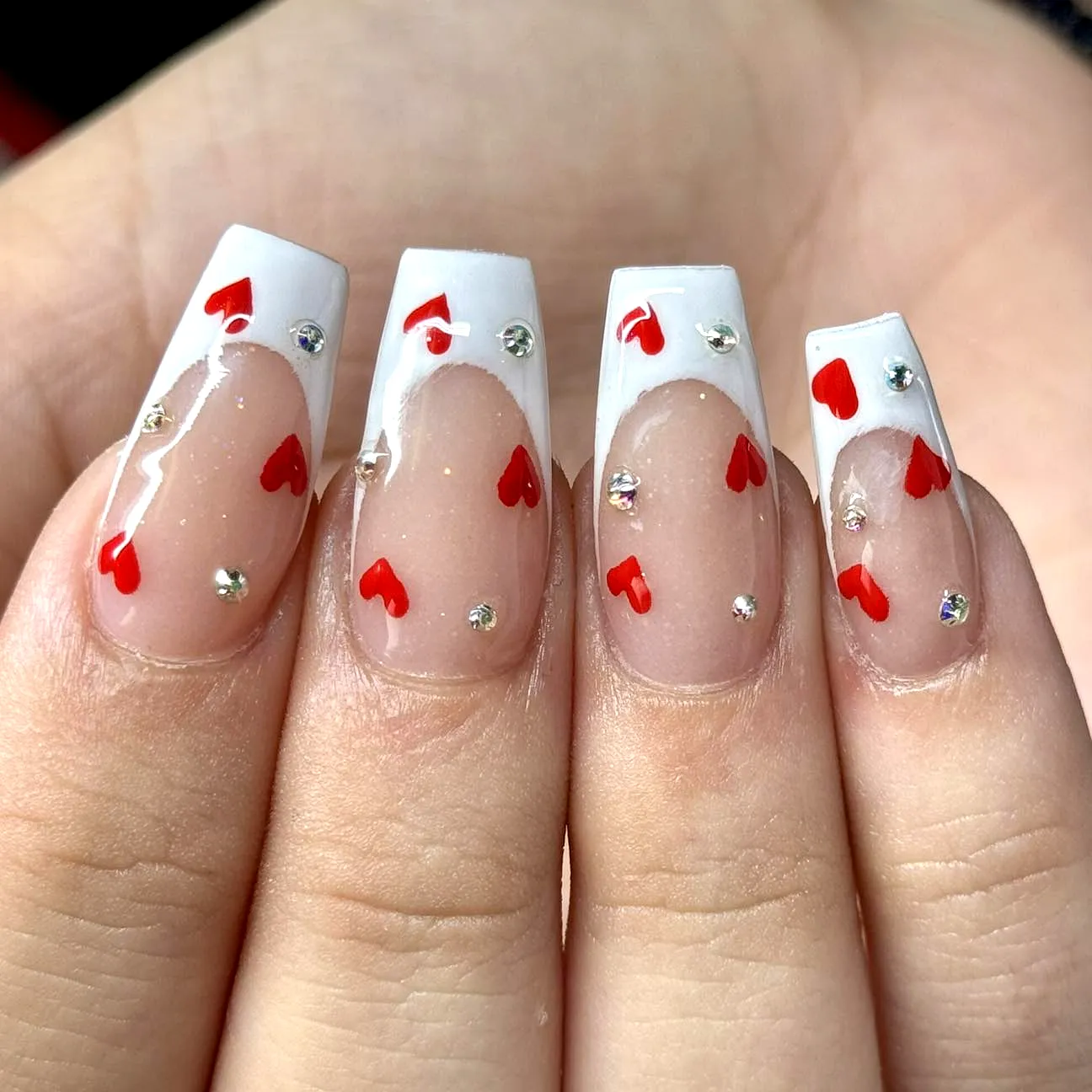 Cute Romantic Valentines Day Nails with Glossy White French Tips Red Hearts and Sparkling Rhinestones on Square-Shaped Nails