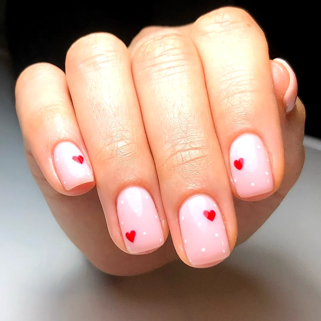 Cute Romantic Valentines Day Nails with Soft Pink Base Delicate Red Heart Patterns and White Polka Dots
