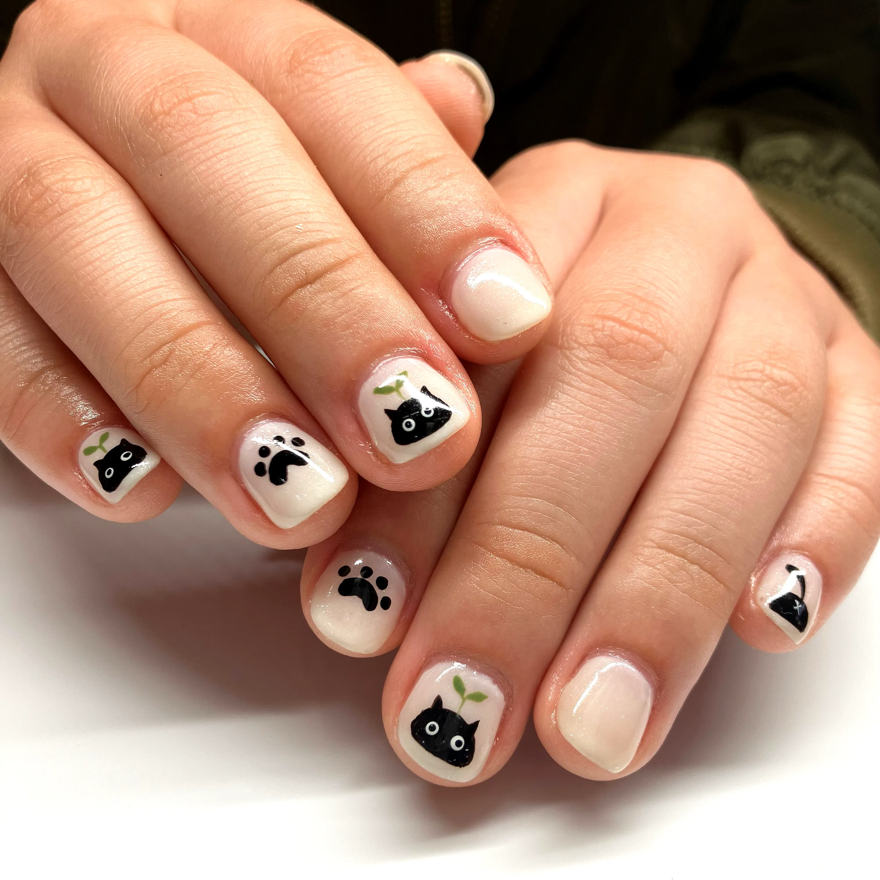 Cute rounded nude black cat nails with paw prints and green leaves