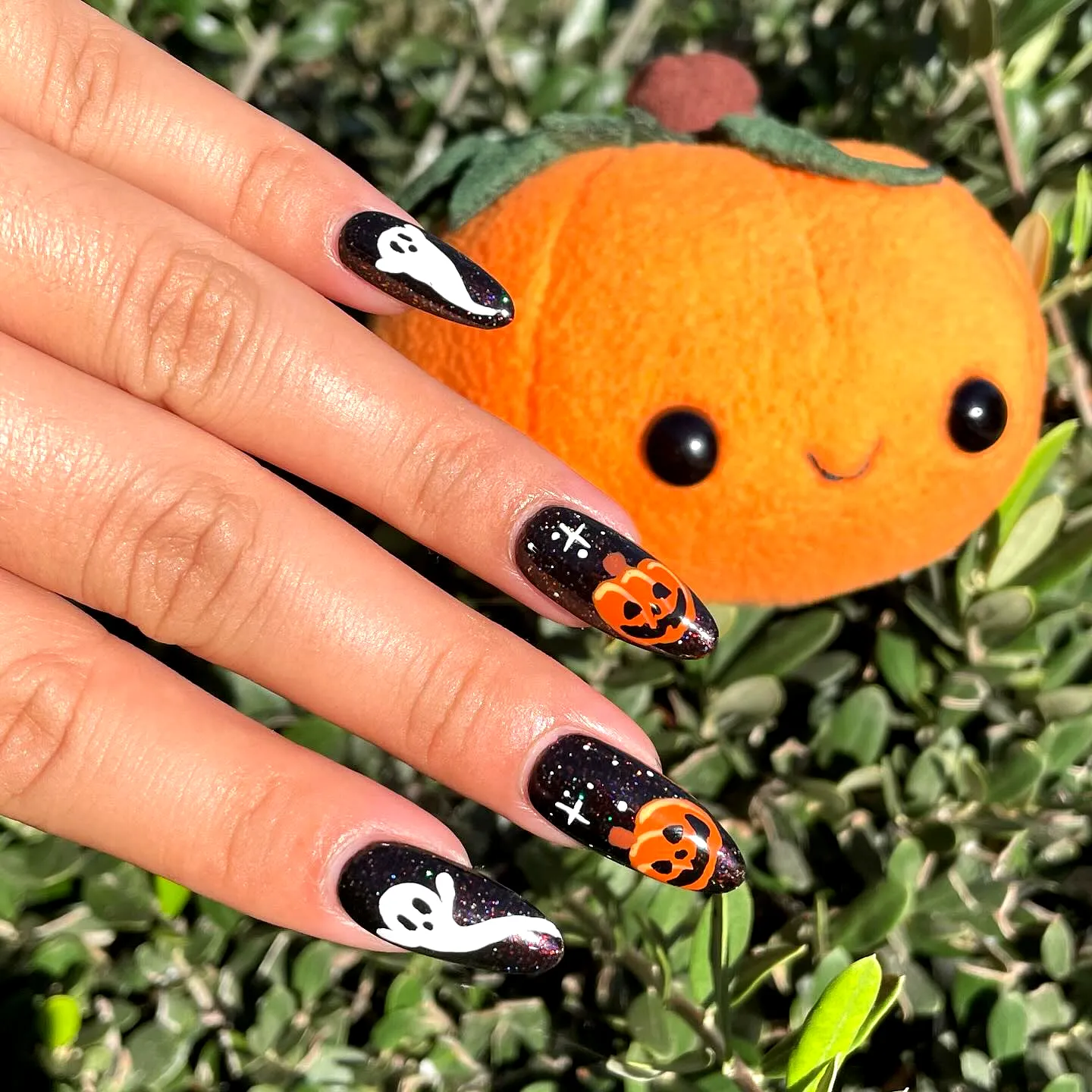 Cute stiletto Halloween nails with black base featuring ghosts and pumpkins