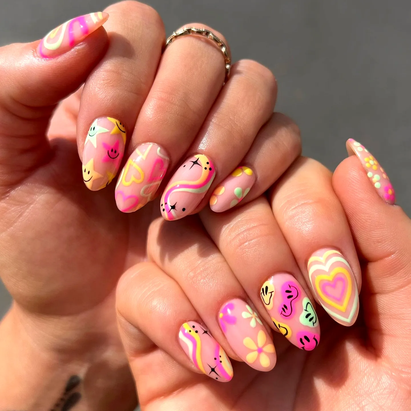 Cute stiletto neon nails with pastel hearts swirls and flowers in vibrant pink yellow and green