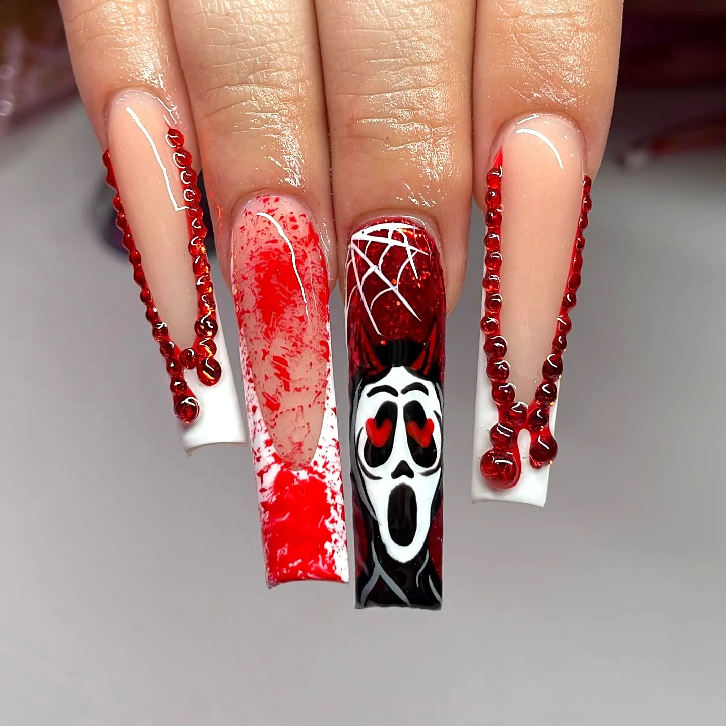 Dramatic coffin-shaped ghost nail designs in bold red white and black with intricate accents and graphic elements