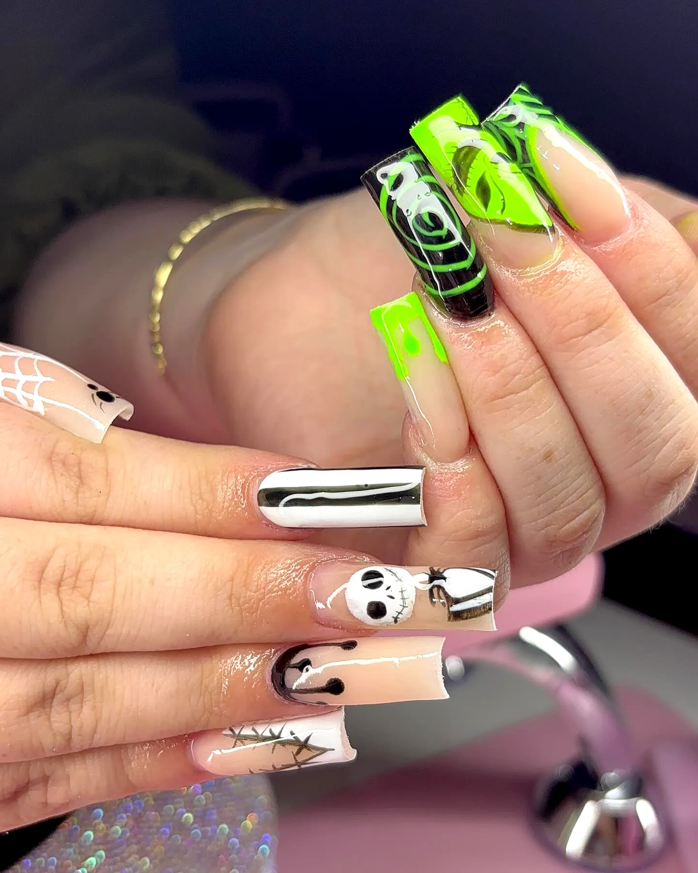 Edgy coffin shaped Nightmare Before Christmas nails with vibrant green black swirls and skull designs