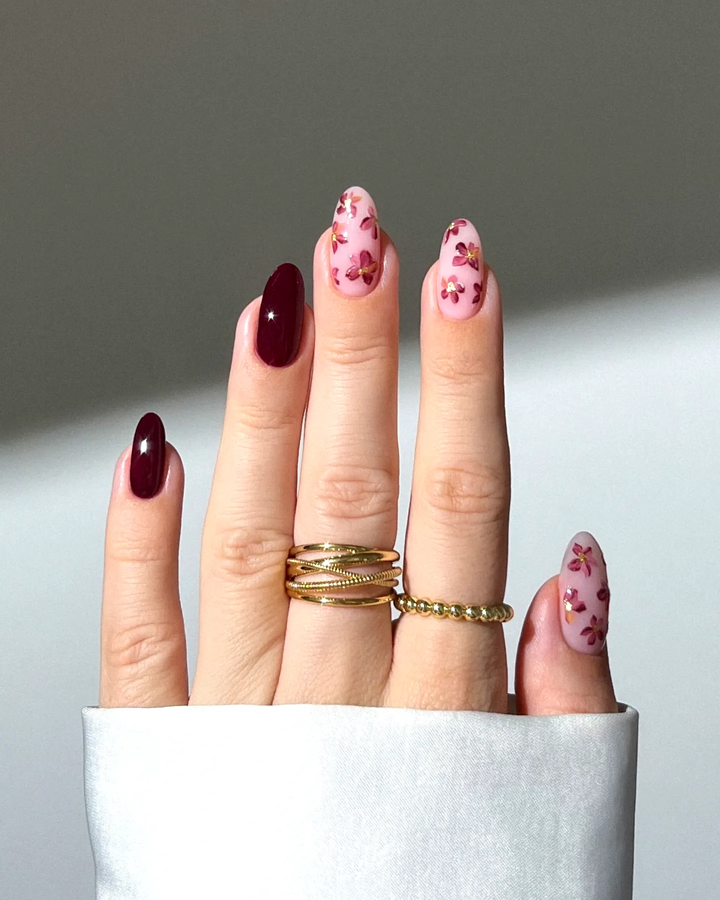 Elegant almond and stiletto classy nail designs in deep burgundy and soft pink with floral patterns and gold embellishments