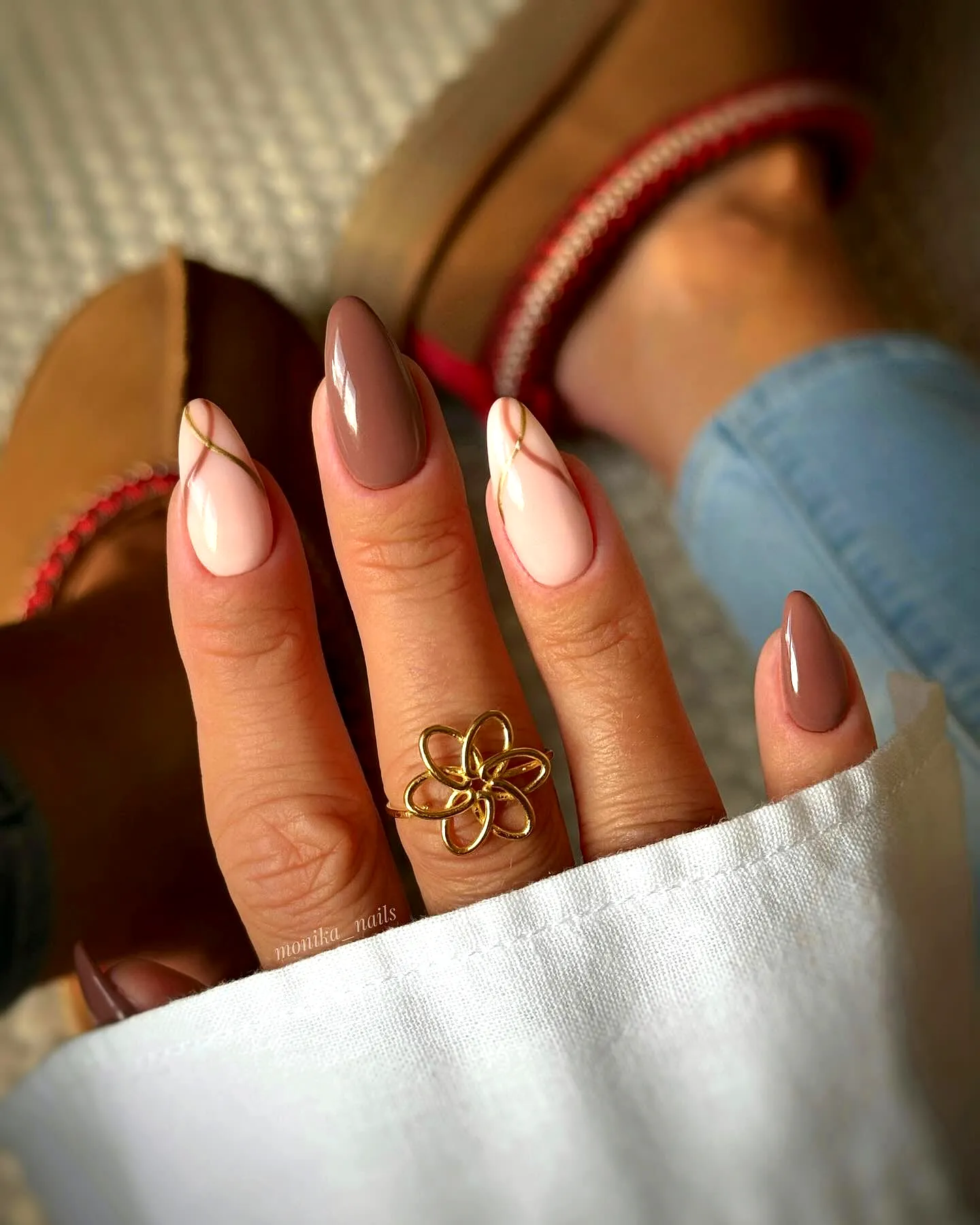 Elegant almond brown nails featuring minimalist gold accents and soft nude hues