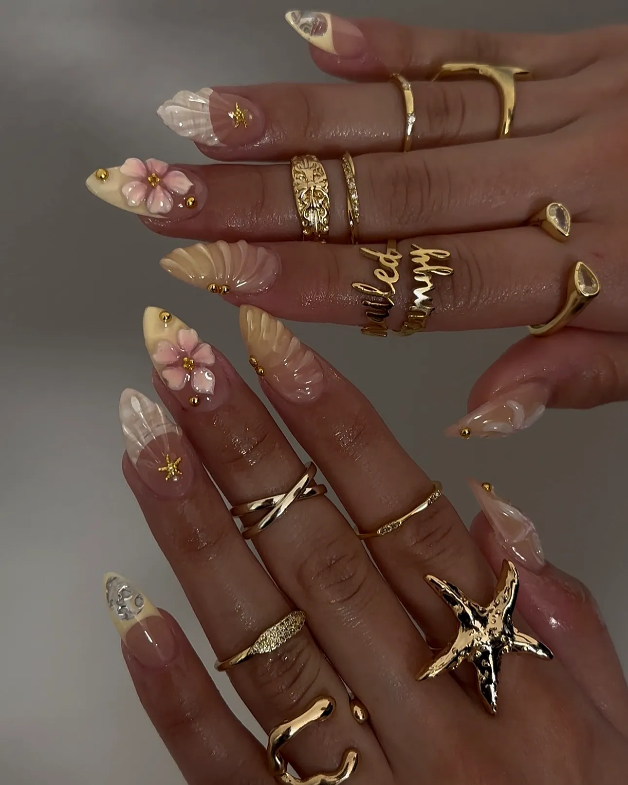 Elegant almond-shaped beach nails with nude base floral designs and gold accents