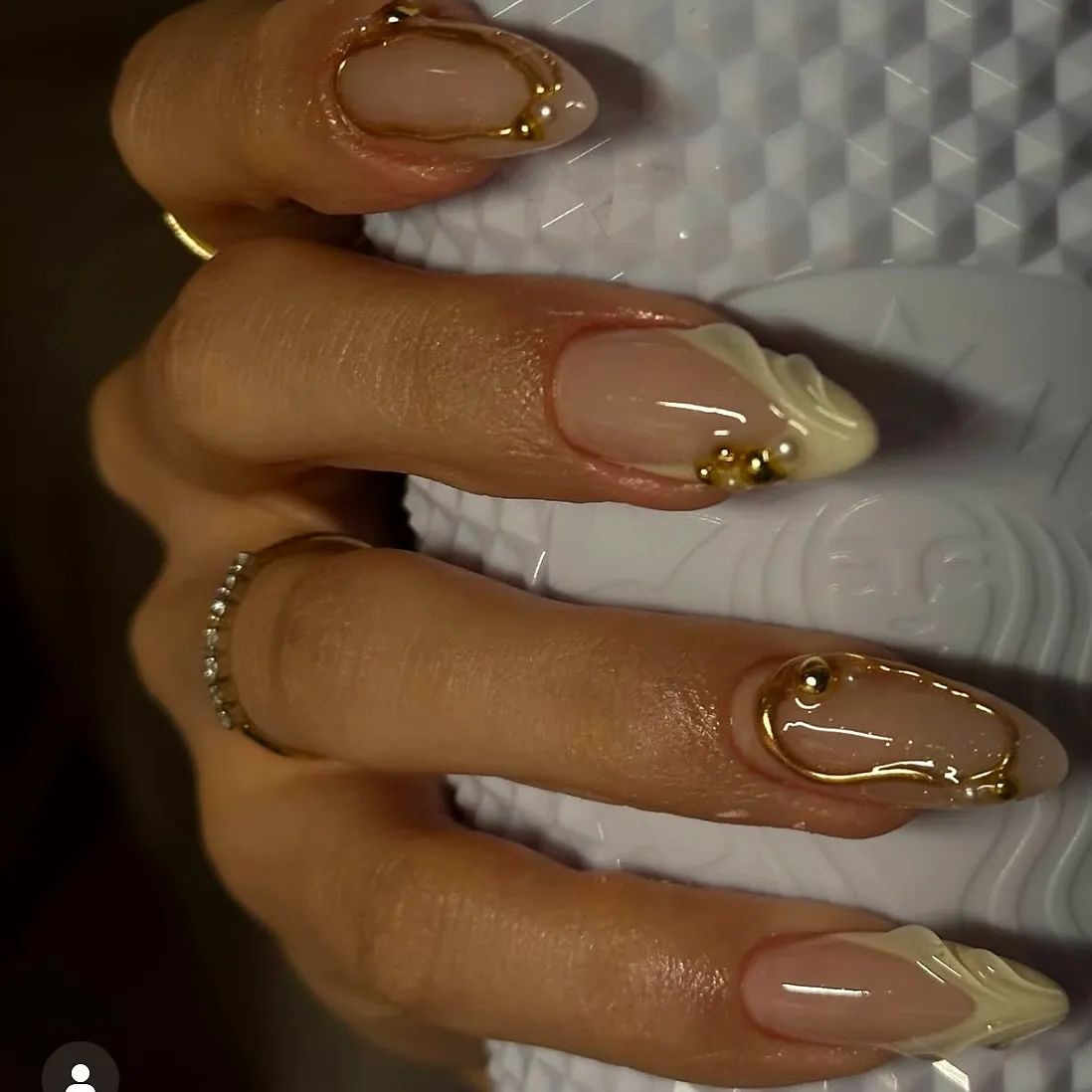 Elegant almond-shaped classy nail designs with nude base white swirls and golden embellishments