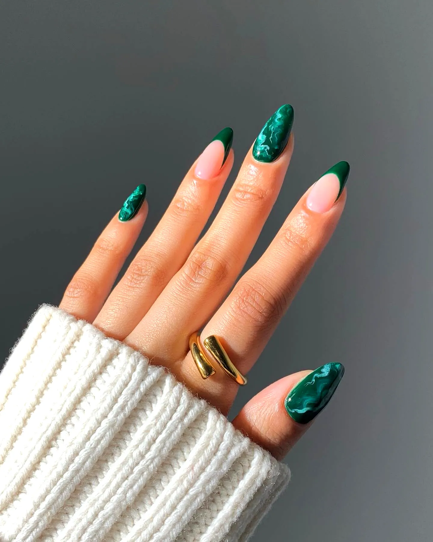 Elegant almond-shaped green nails with marble effect design on nude base