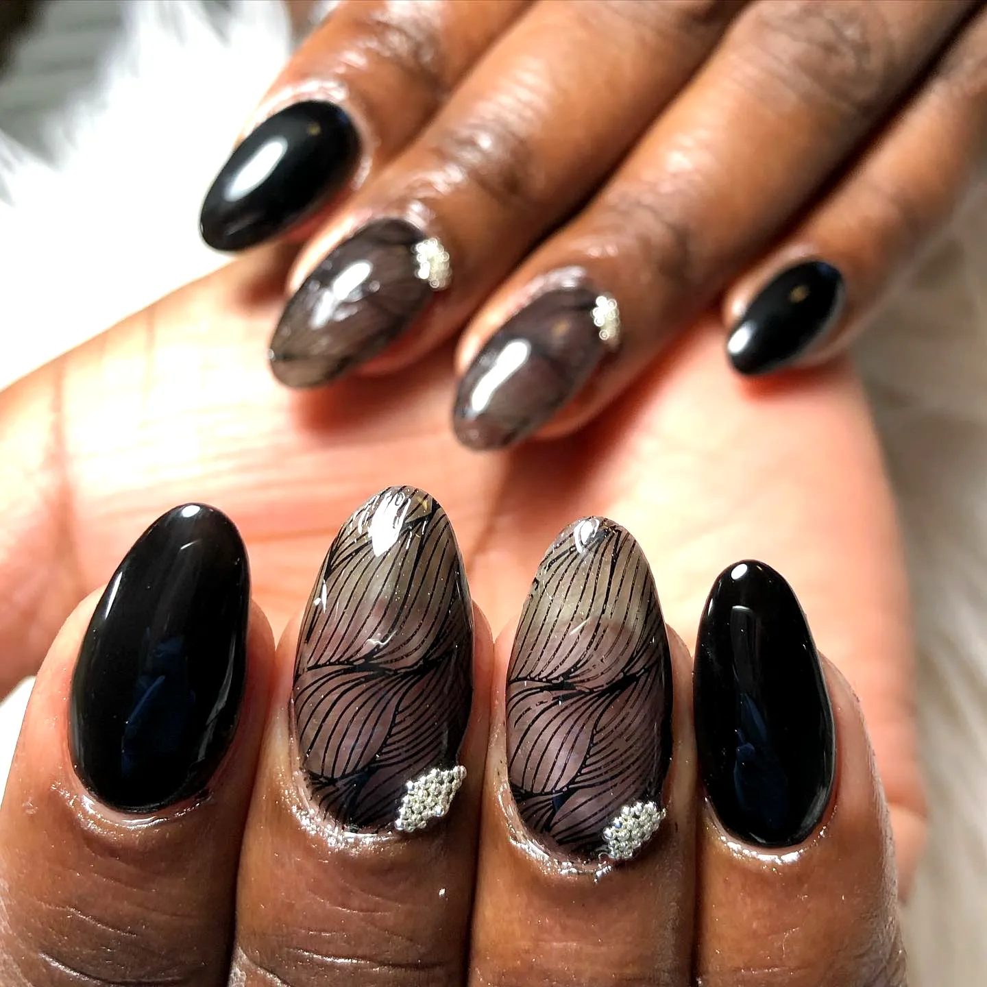 Elegant almond shaped lace nails with glossy black finish and delicate feather accents