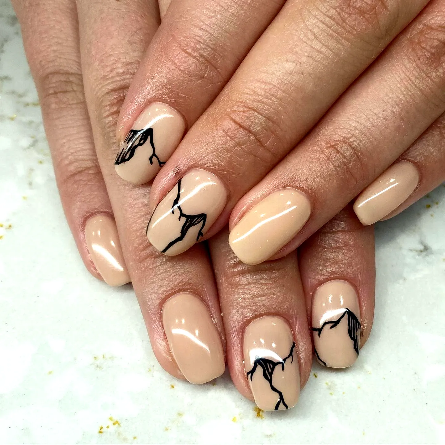 Elegant almond shaped mountain nails with soft nude base and artistic black line work
