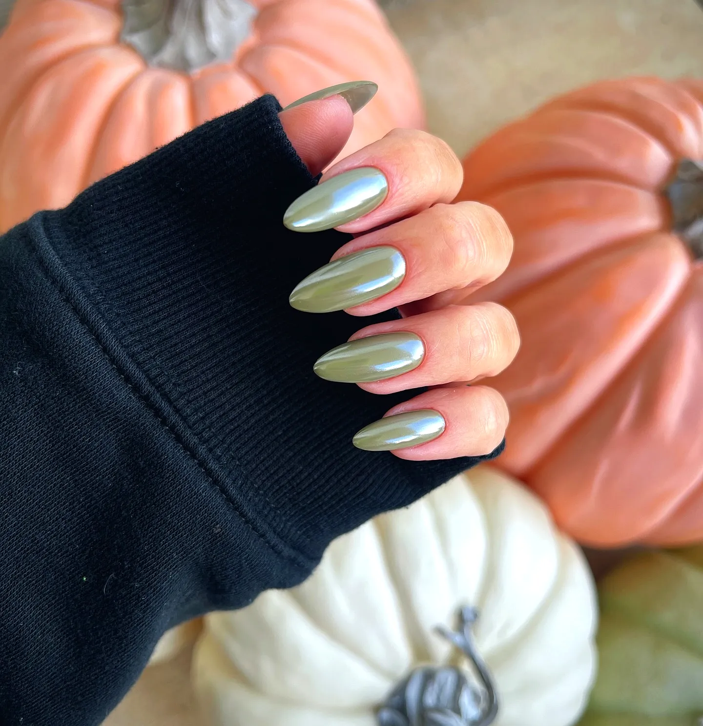Elegant Almond-Shaped Olive Green Nails with Glossy Finish and Seasonal Pumpkin Backdrop