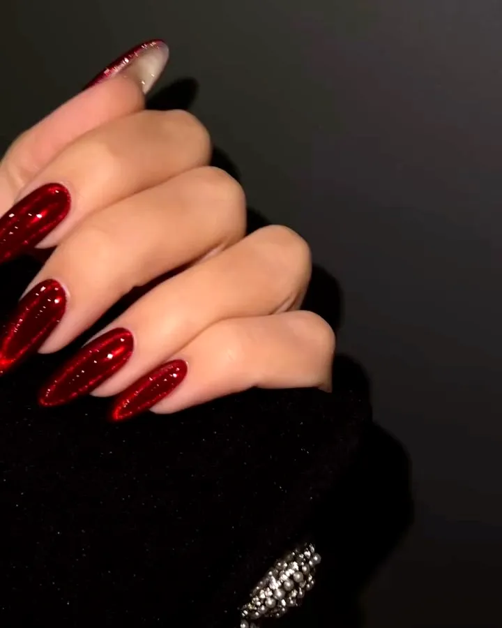 Elegant almond-shaped red nails with glossy shimmer and stylish contrast