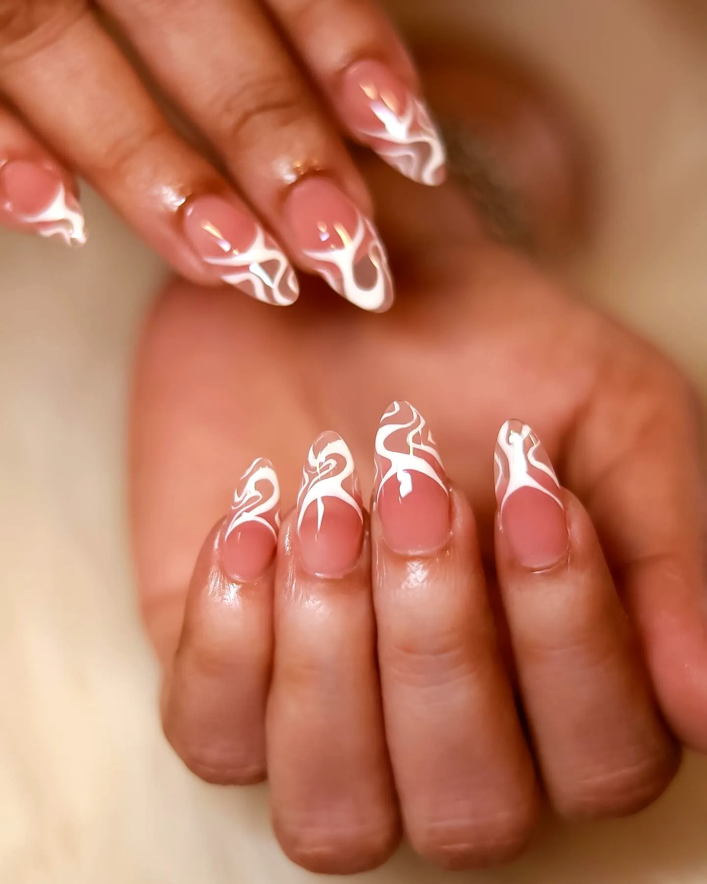 Elegant almond-shaped swirl nail designs with a natural pink base and white flame-like swirls