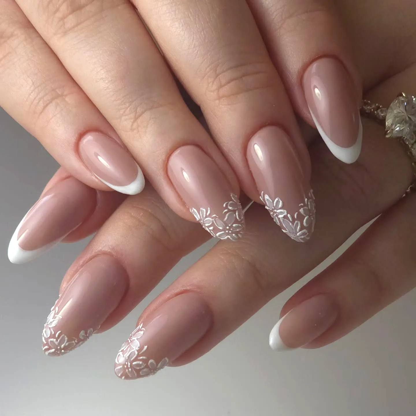 Elegant almond-shaped wedding nails with nude base and floral French tips