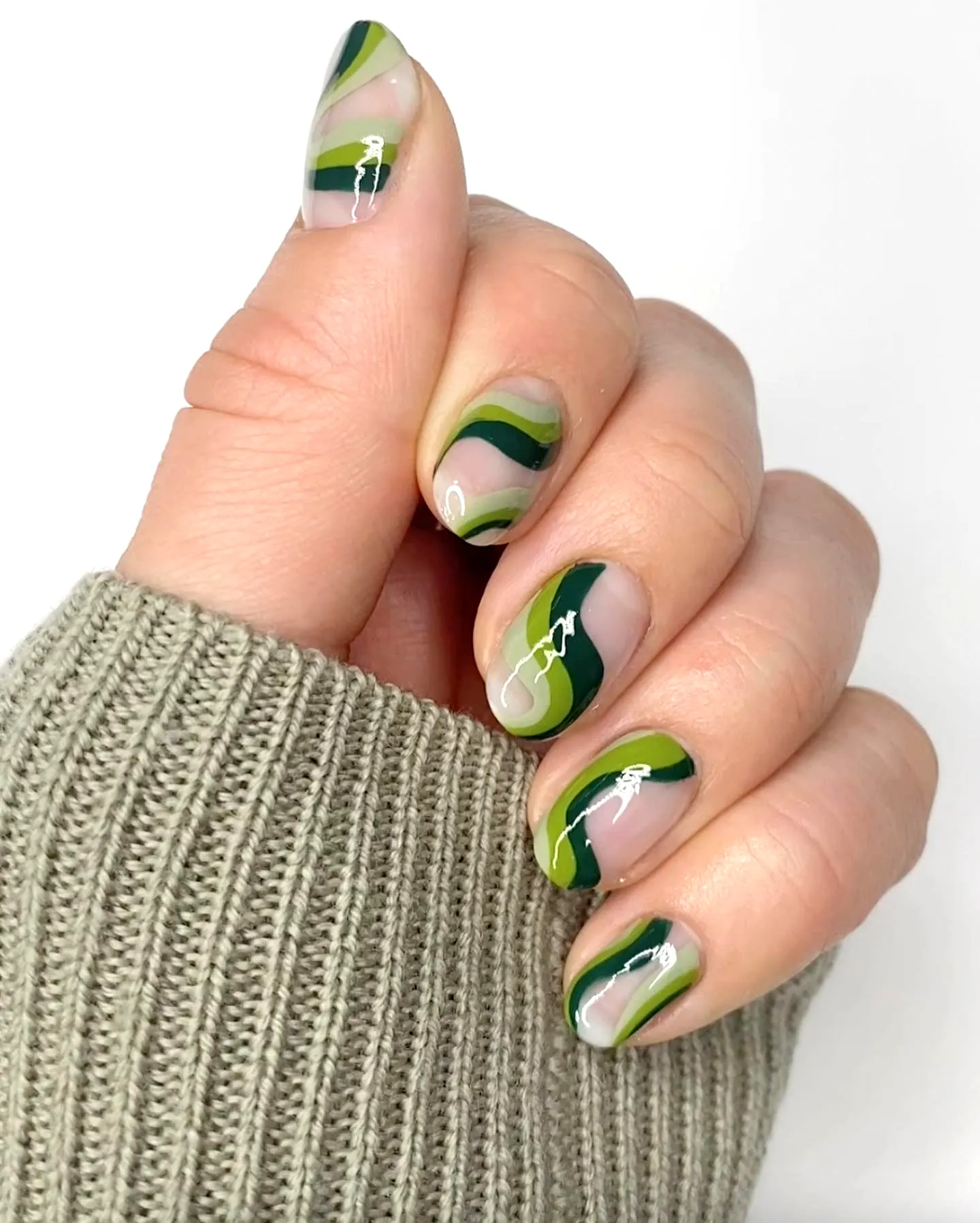 Elegant almond swirl nail designs in green with fluid patterns and white accents