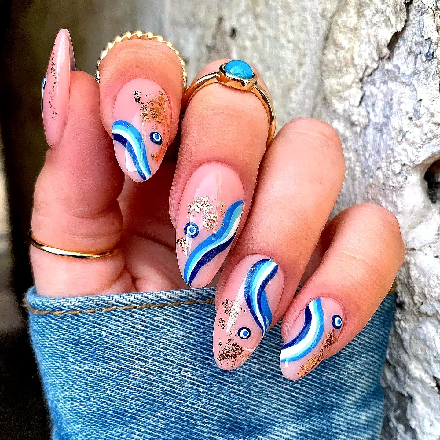 Elegant almond swirl nail designs in soft pink with blue patterns and gold glitter