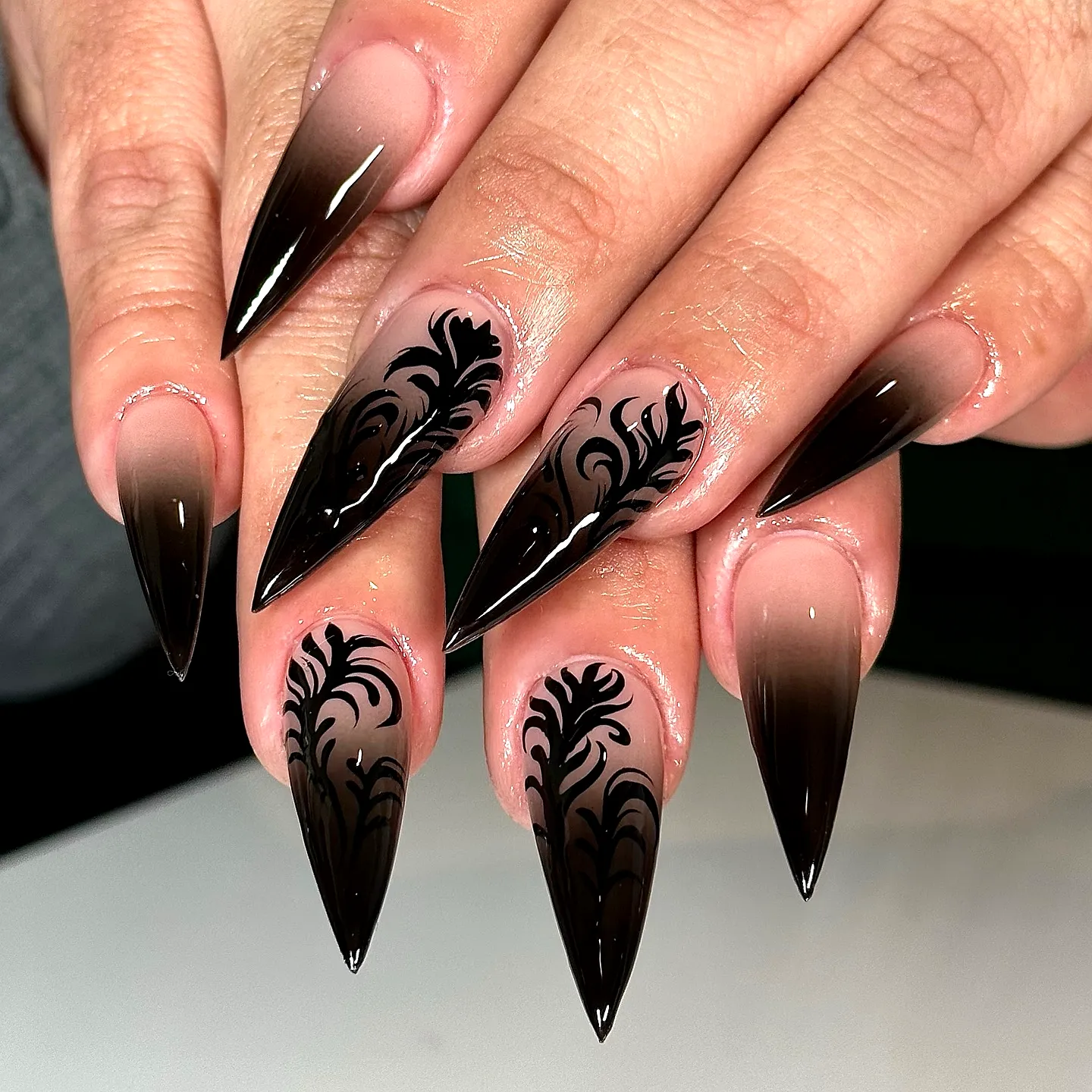Elegant long stiletto black birthday nails with glossy gradient and floral art