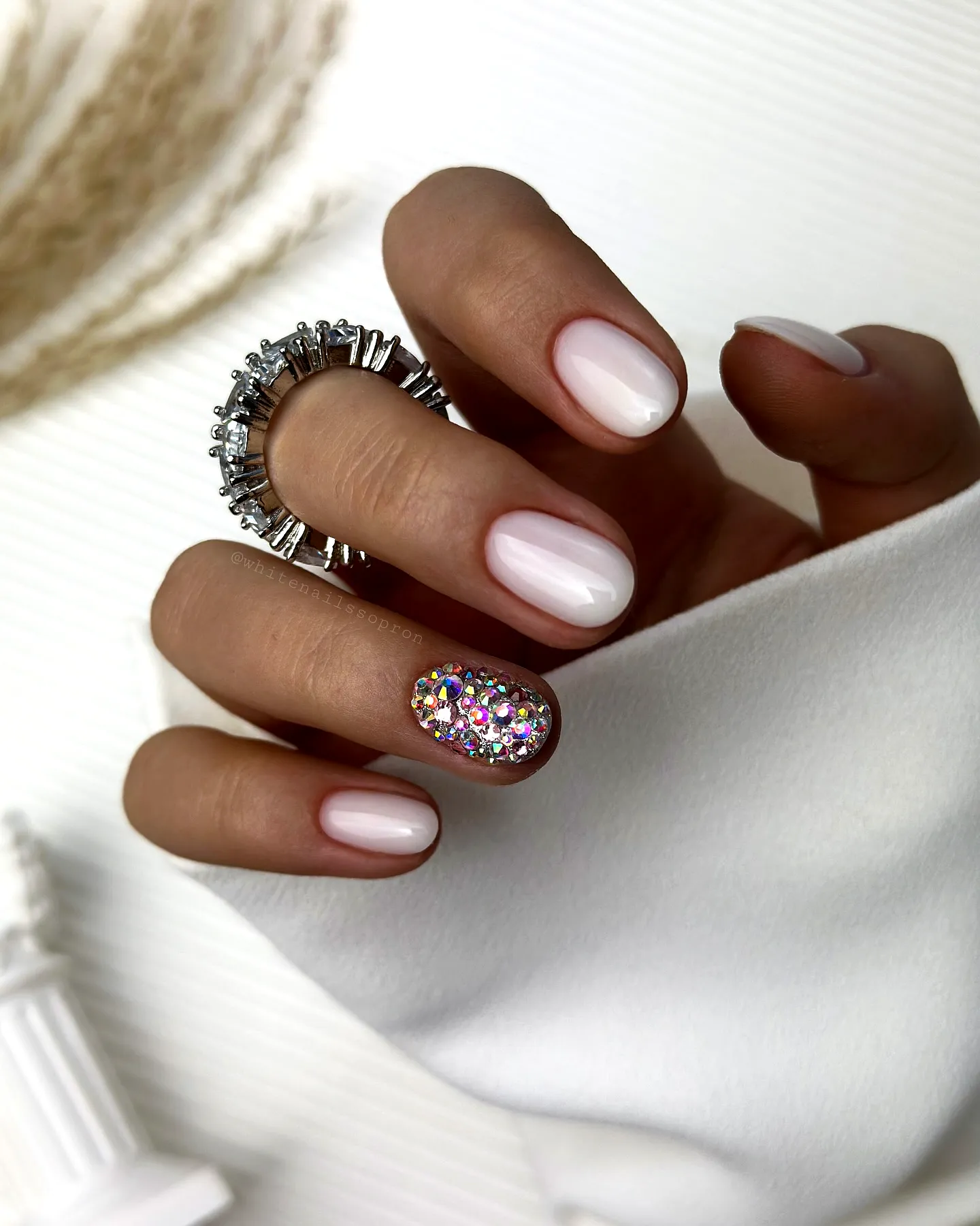 Elegant oval white nails with colorful rhinestone accents for a modern chic look