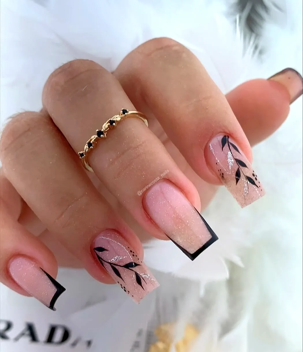 Elegant square luxury nails with soft pink gradient and glitter fade featuring black leaf patterns and geometric tips