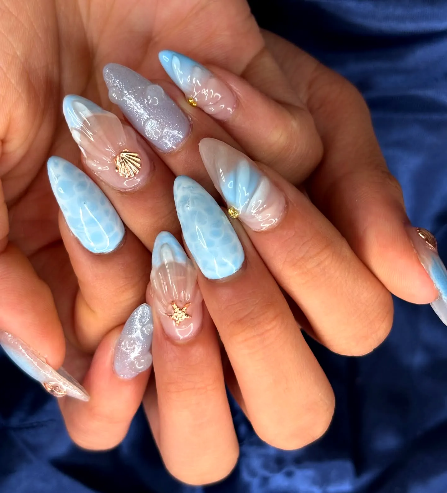 Elegant Stiletto Beach Nails in Light Blue with Seashell Motif and Glitter Finish