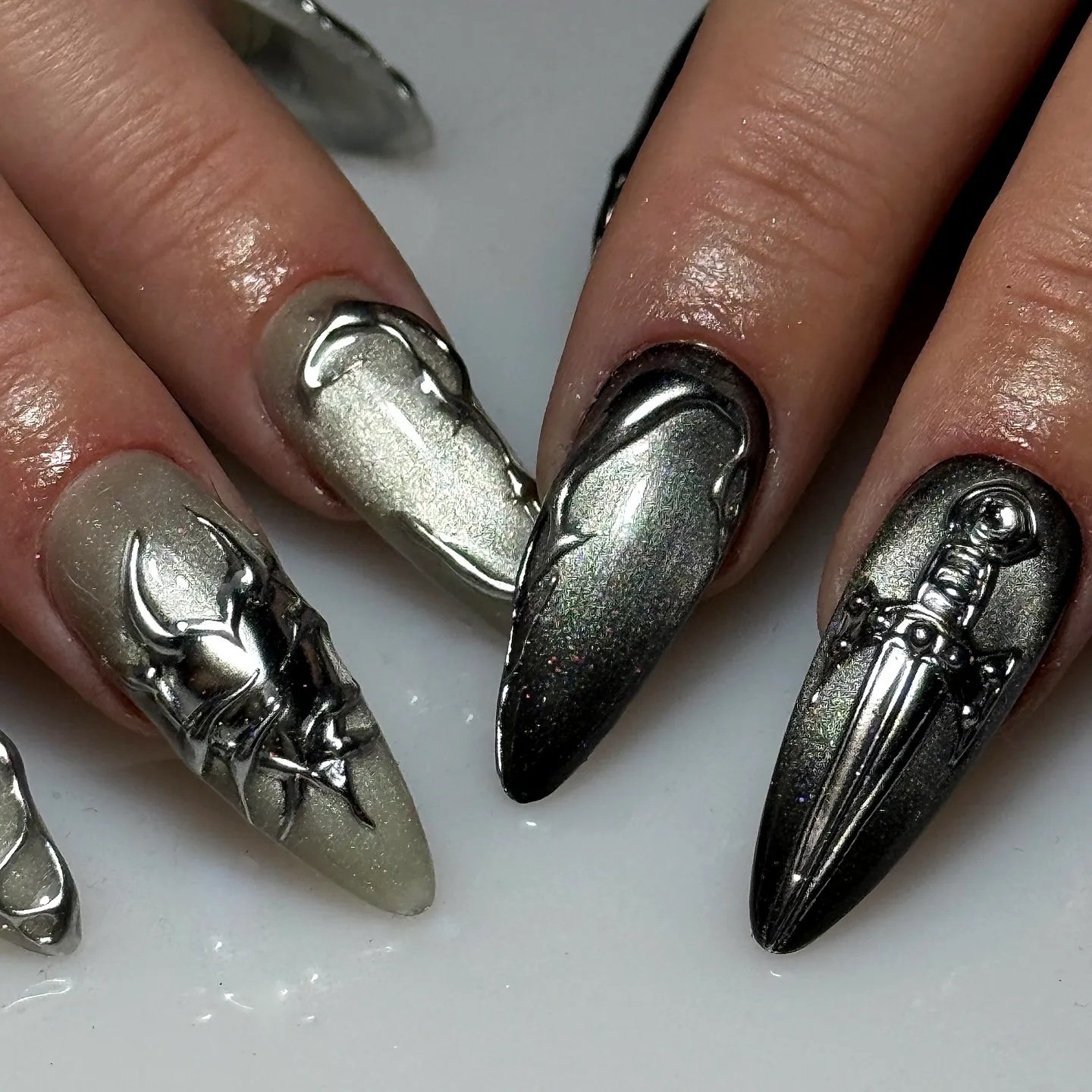 Elegant stiletto dark wedding nails with metallic silver and black sword and horn motifs