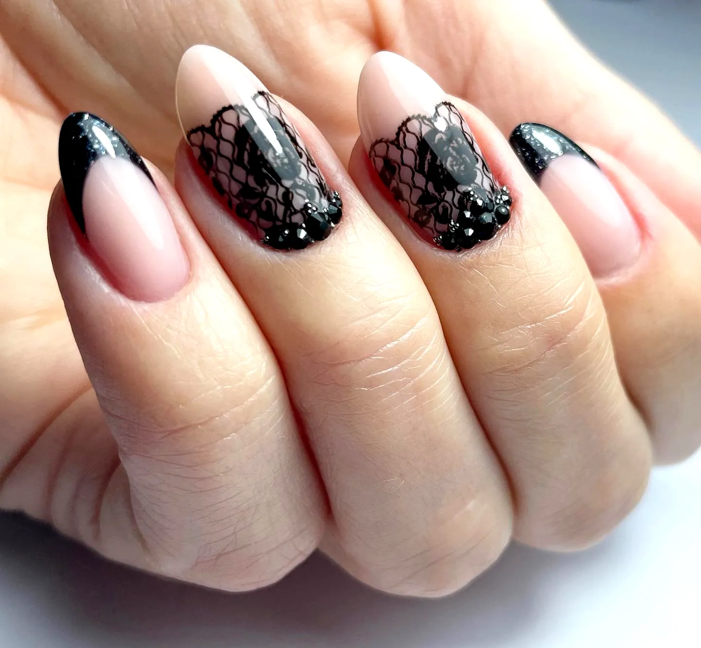 Elegant stiletto lace nails with glossy black French tips and gemstone accents